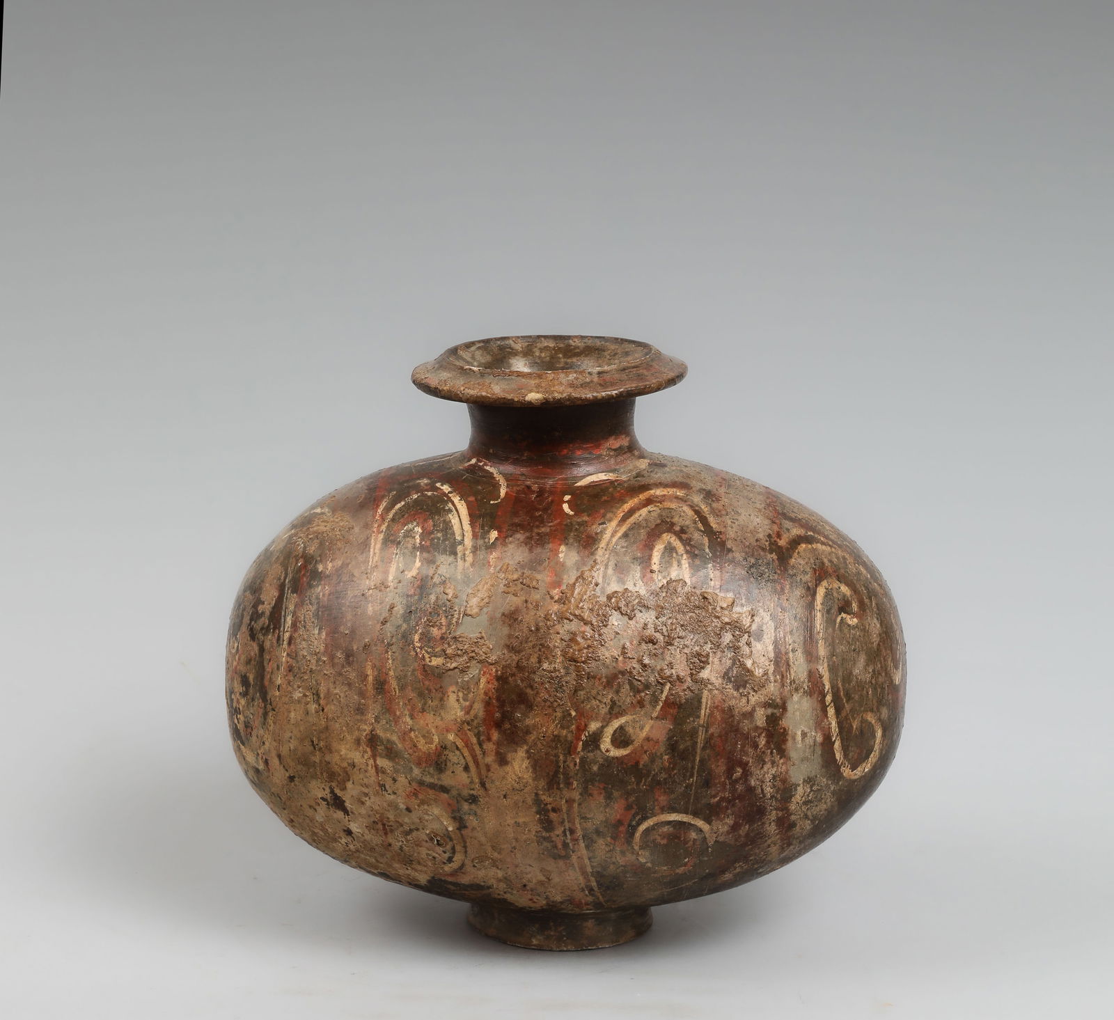 "Cocoon" Vase, Chinese Culture, Han Dynasty, 3rd Century BC – 3rd Century AD: Modeled and painted terracotta. Measures 25 x 29 x 11 cm. This globular vessel has a gently flattened profile, a short neck, and a slightly everted rim. Its surface is articulated by a delicate decora
