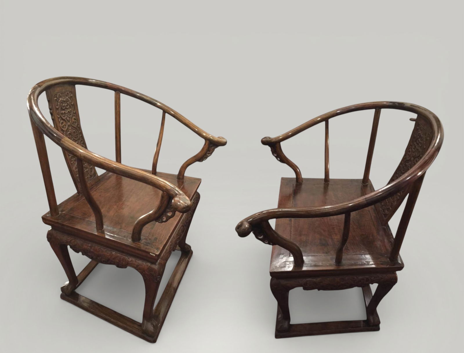 Pair of "bonnet de lettré" backrest armchairs, Qing Dynasty, 18th-19th century: Carved and assembled wood. Dimensions: 107 x 80 x 80 cm. Pair of Chinese armchairs with a curved backrest in the shape of a "lettre bonnet," characteristic of scholarly furniture. The enveloping line