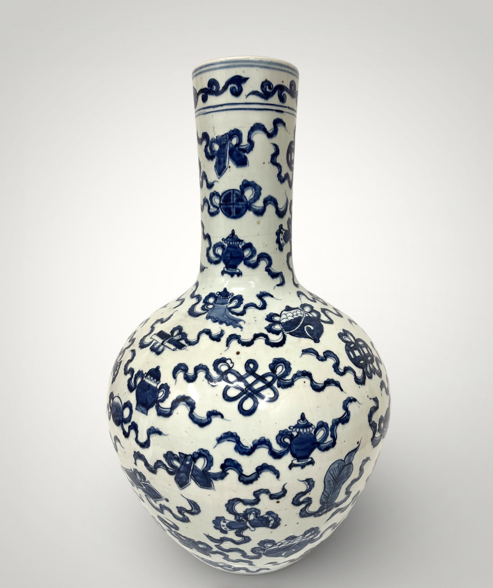 Large Tianqiuping vase with Buddhist emblems, Chinese production, Qing Dynasty, 19th century: White porcelain with cobalt blue underglaze decoration. Measures 66 x 13 cm. Large Tianqiuping-style vase, characterized by its slender cylindrical neck and wide, globular body, decorated with a refin