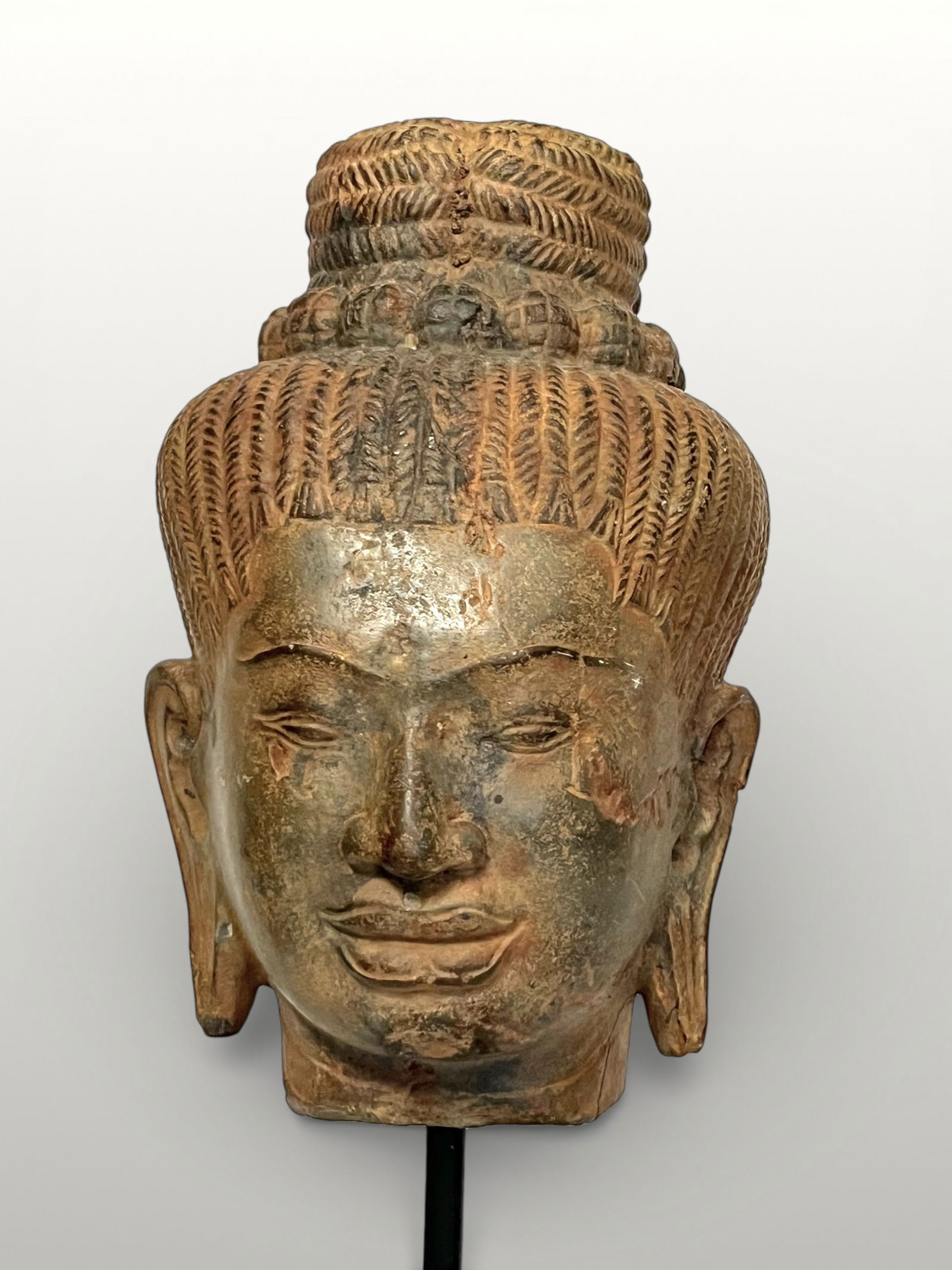 Head of Shiva, Khmer art, Bayon period, Cambodia, 12th - 13th century: Sculpted beige sandstone. Head of Shiva adorned with a high topknot finely incised into stylized braids, held by a pearl ring reminiscent of the jata-mukuta. The face is softly and harmoniously modele