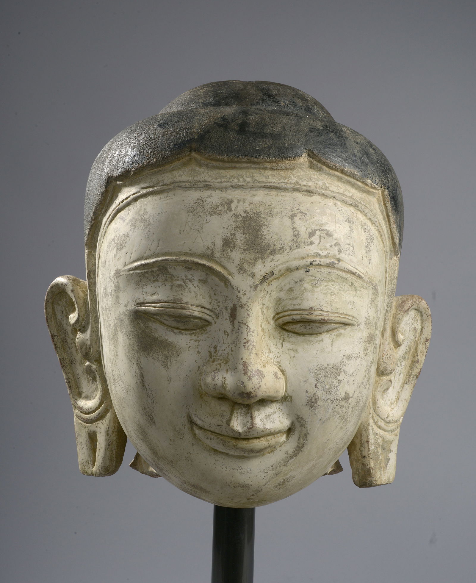 Buddha head, Pagan Kingdom, Burma, 17th century: Sculpted gray sandstone, polychromed in black and white. A Buddha head with a serene expression, characterized by half-closed eyelids that encourage introspection, defined lips forming a slight, beati