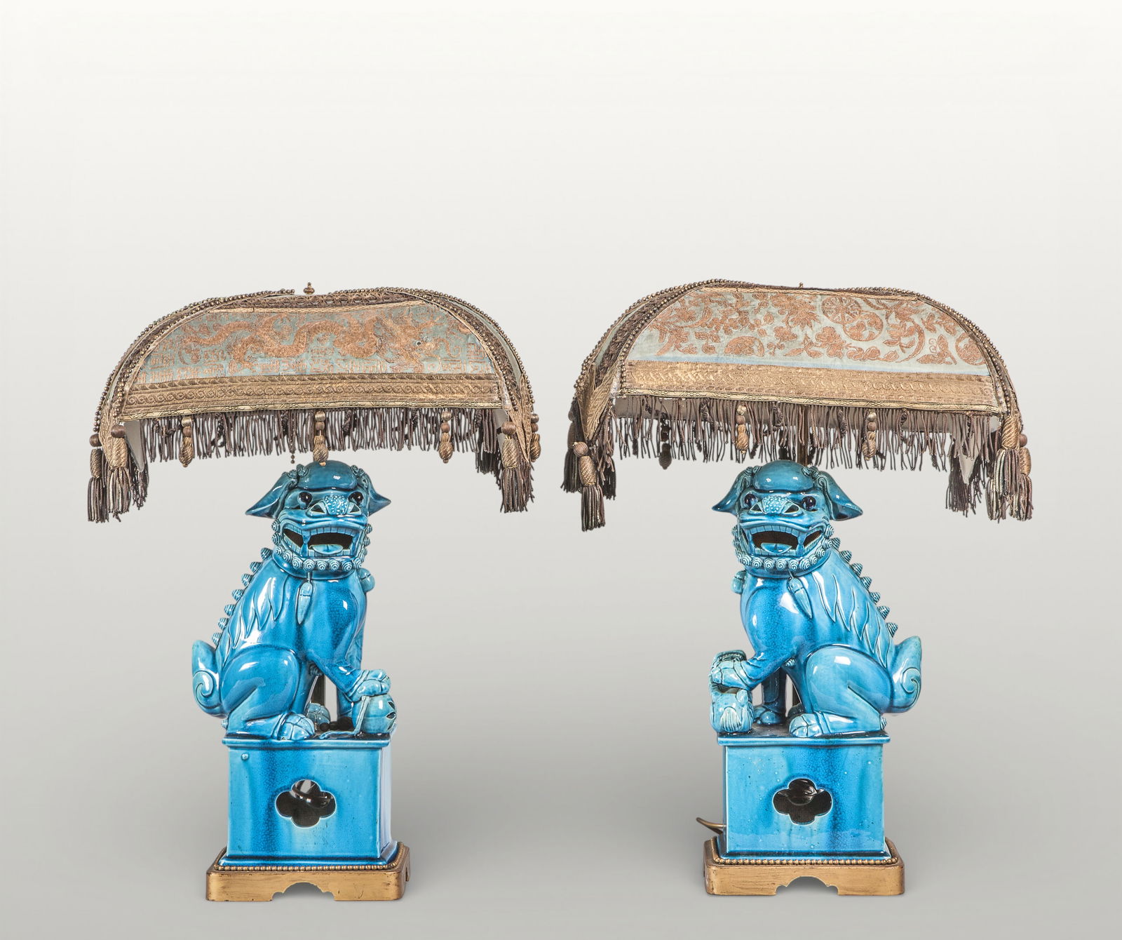 Pair of Foo dogs, Chinese porcelain in the decorative tradition, 20th century: Porcelain with a turquoise monochrome glaze. A pair of Fo dogs are arranged symmetrically, seated on rectangular pedestals, adopting vigilant and protective postures. Their robust bodies are modeled w