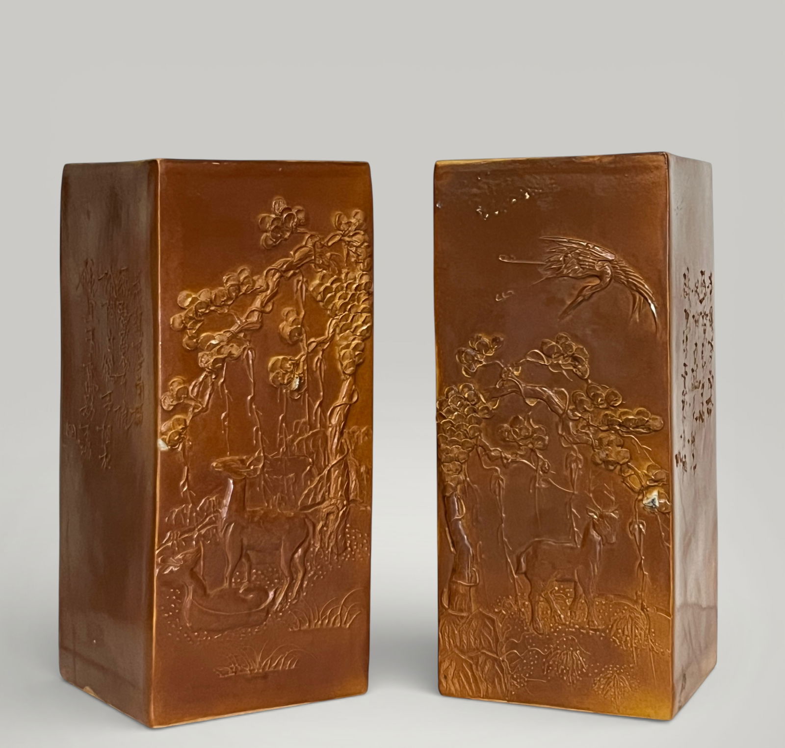 Pair of scholar's brush holders, China, Qing Dynasty, 19th Century: Porcelain with a monochrome caramel glaze. Measures 28.5 x 12 x 12 cm. A pair of rectangular objects, designed as brush holders for a scholar's desk, decorated in low relief on all four sides with a r