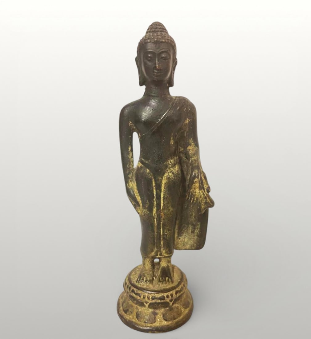 Standing Buddha, Central Java, Sailendra School, 9th Century: Cast bronze. Measures 17 cm. Figure of Buddha depicted standing on a small circular base decorated with stylized lotus petals, adopting an elegant and balanced pose, with his right arm relaxed at his