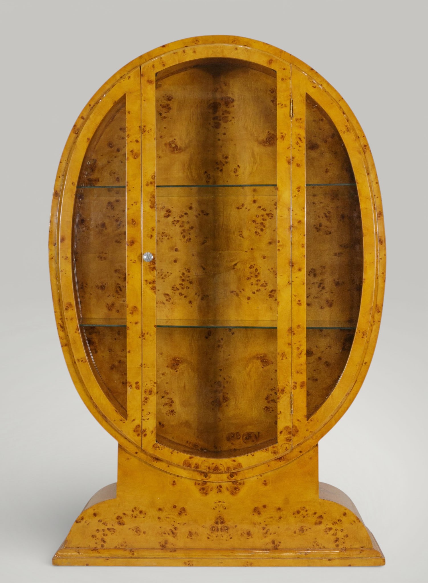 Oval display case on a pedestal. Art Deco style. 20th century.: Elm burl veneer. Dimensions: 160 x 102 x 32 cm. This elegant oval-shaped display cabinet sits on an integrated pedestal, reinforcing its sculptural and monumental presence. The front features double g
