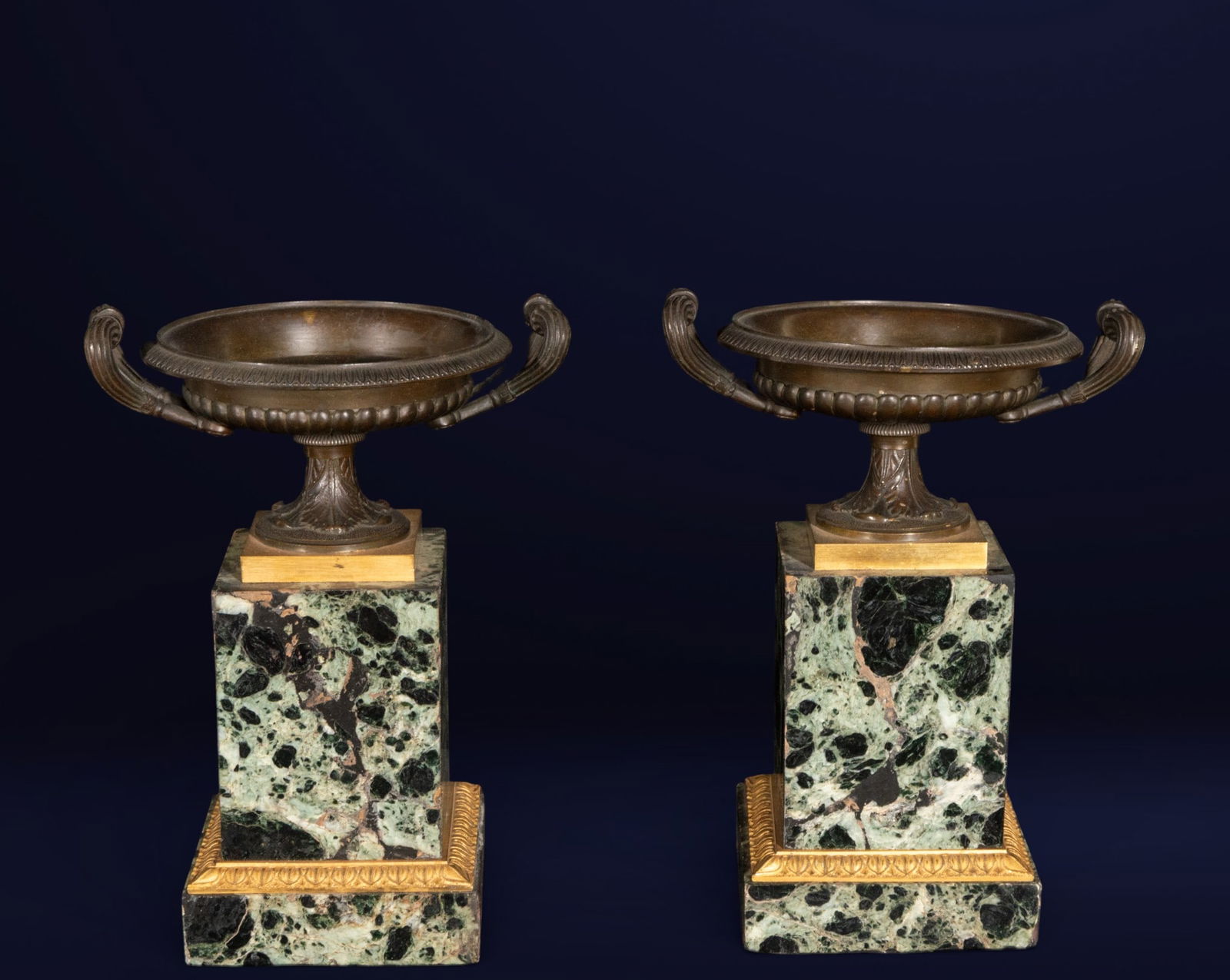 Pair of clock surround cups, French School, Early 19th Century: Marble and gilded and patinated bronze. Measures 24 x 17.5 x 14 cm.
