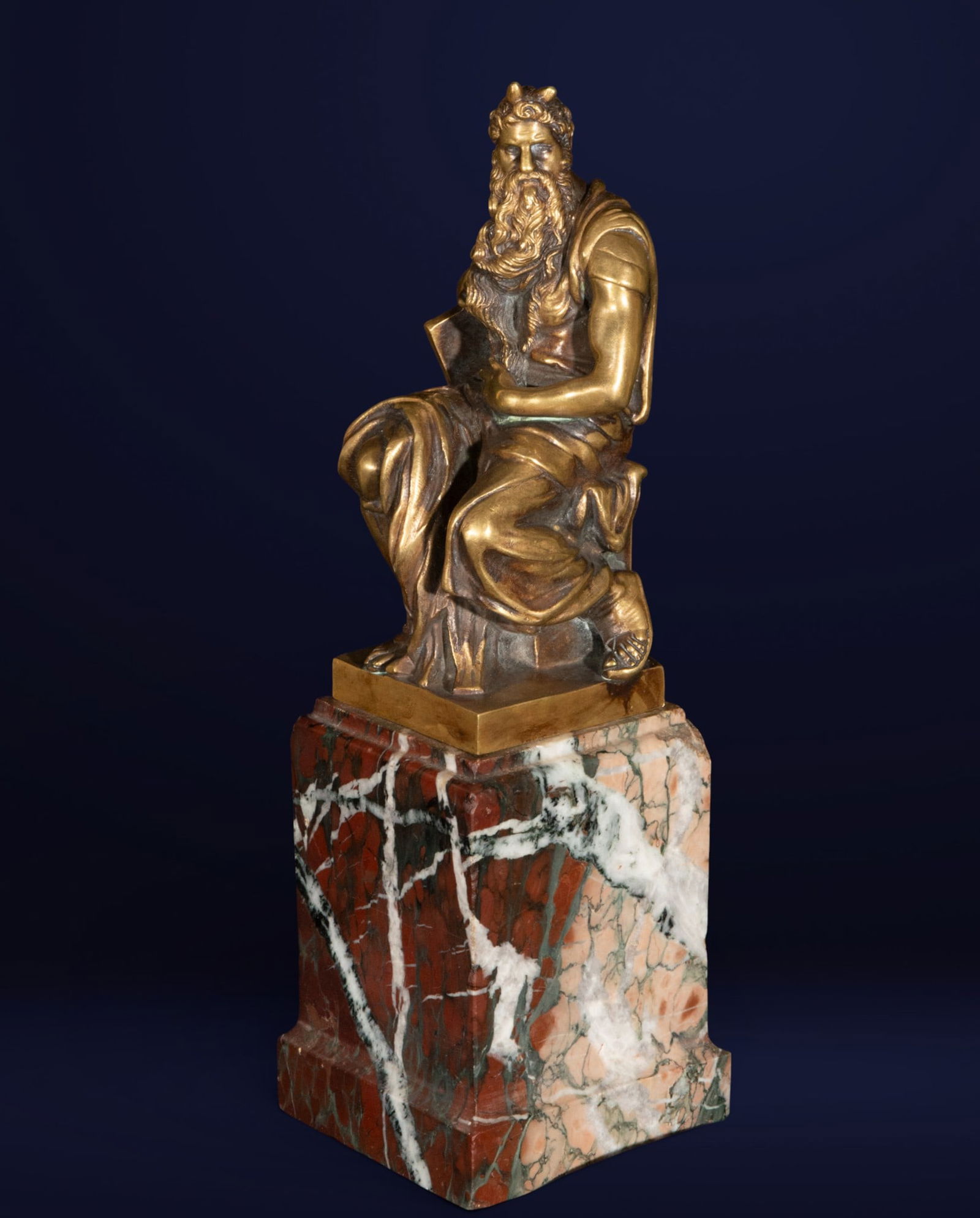 Moses, Grand Tour School, 19th Century: Cast bronze, chased and gilded on a marble base. Measures 33 x 11 x 10 cm. This sculpture depicts a seated Moses, with a powerful presence and focused expression, his beard and hair rendered with grea
