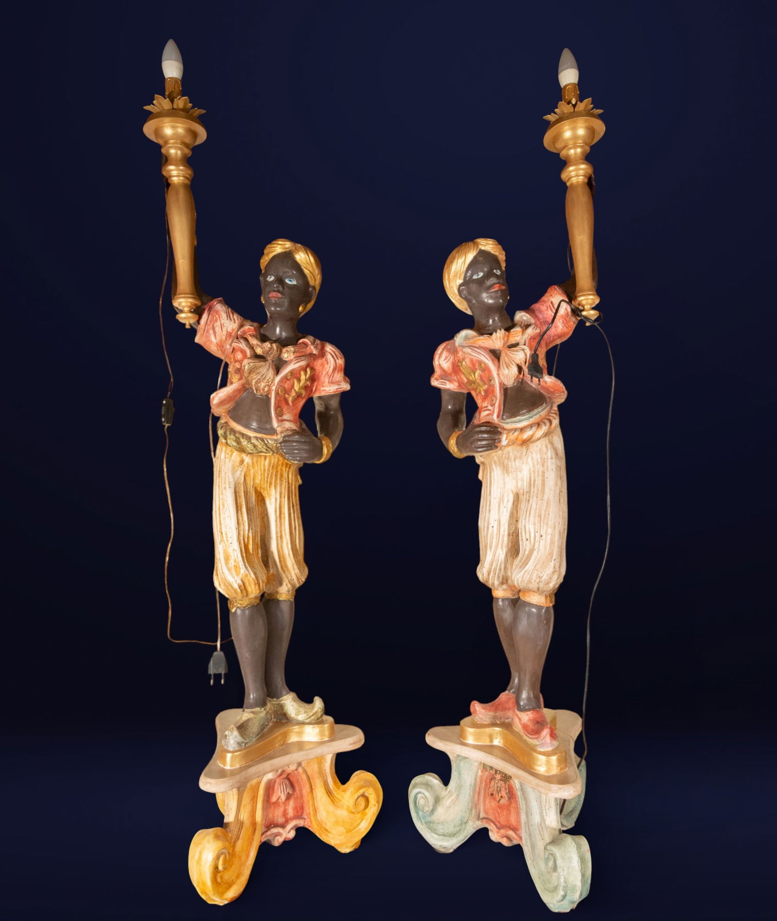 Pair of Venetian Moretto torchbearers. Italian school. 20th century.: Carved and polychromed wood with metal elements. Measures 143 x 38 x 38 cm. Pair of large-format lamp-bearing figures, conceived as exotic characters holding aloft their arms carrying light, integrati