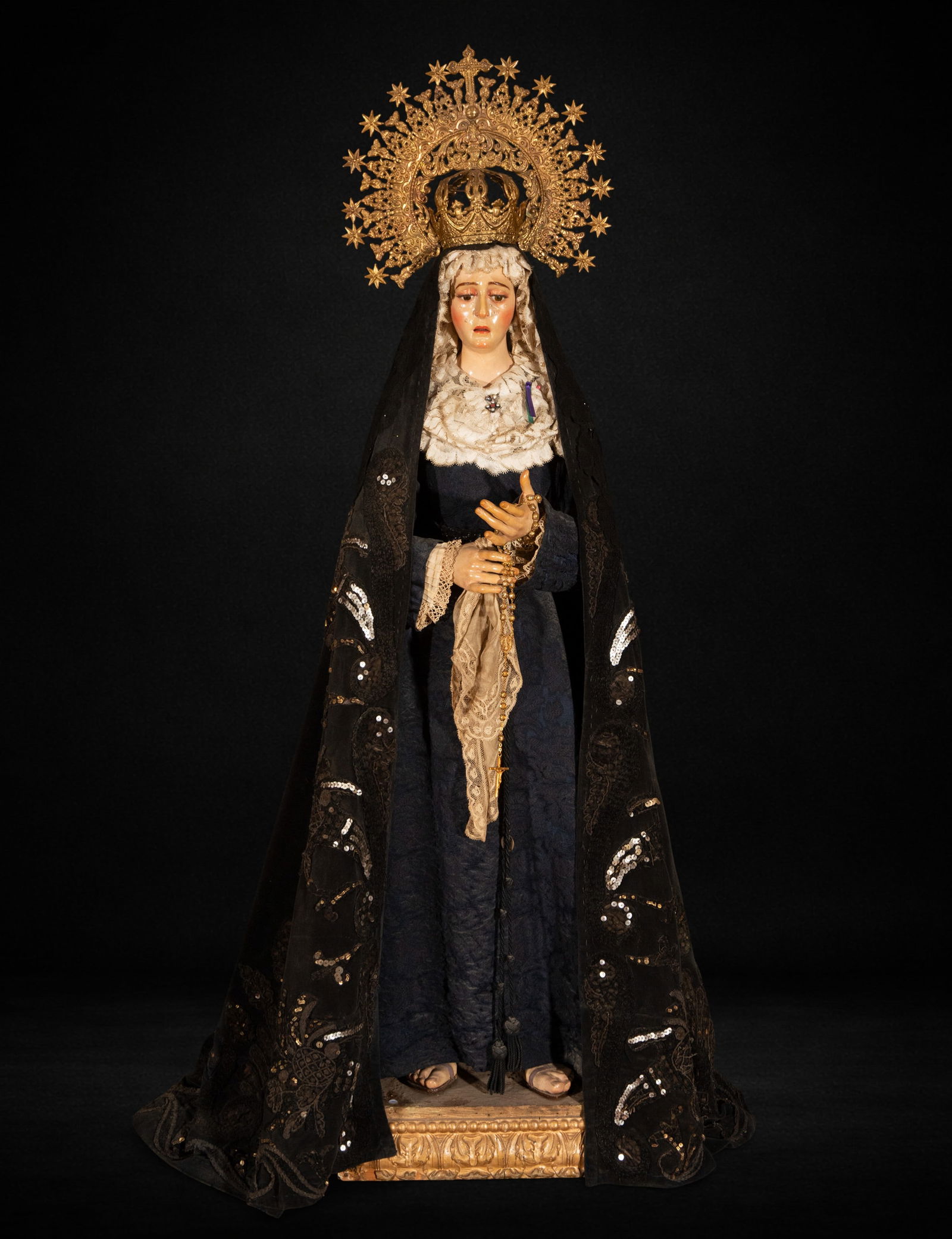 Dressed image of the Virgin Mary. 19th century.: Polychrome wood carving for dressing. Measures 108 x 39 x 31 cm. The Virgin appears upright, with one hand extended and the other holding a gold rosary, a gesture that reinforces her meditative and pe
