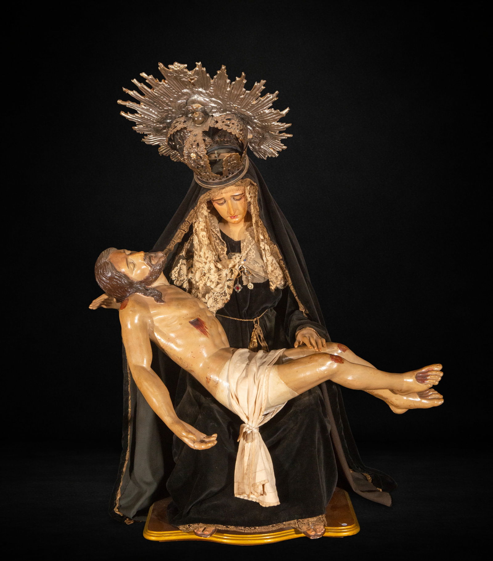 Dressed Pietà. Late 18th – early 19th century: Polychrome wood carving for dressing. Measures 88 x 72 x 45 cm. The composition shows the Virgin Mary holding the lifeless body of Christ in her lap, creating a diagonal arrangement that intensifies t