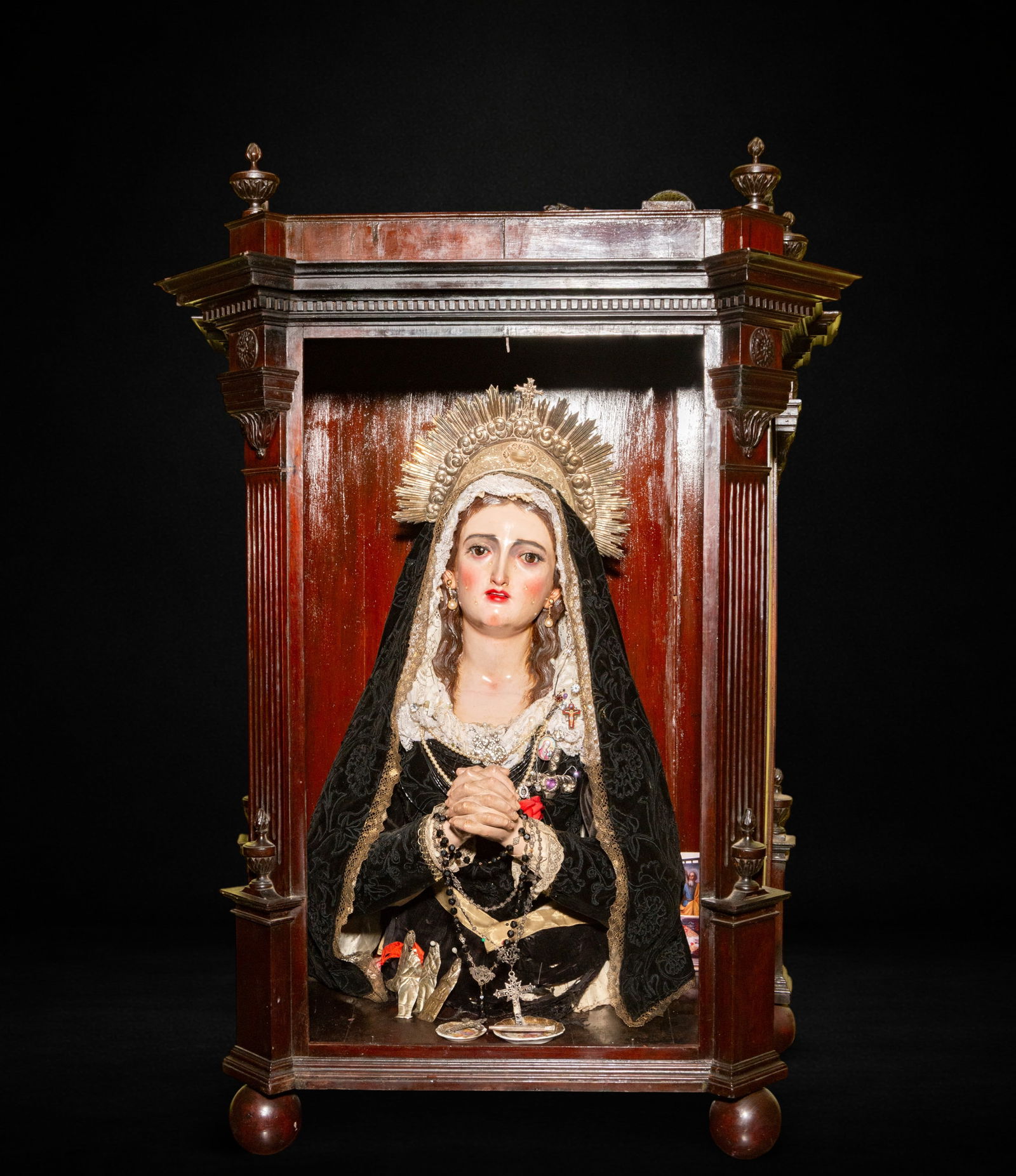 Dressed Virgin Mary. 18th Century: Polychrome wood carving for dressing. Dimensions: 67 x 35 x 25 cm; display case: 72 x 44 x 30 cm. The image is depicted in a praying posture, with hands clasped in front and an upward gaze that accent