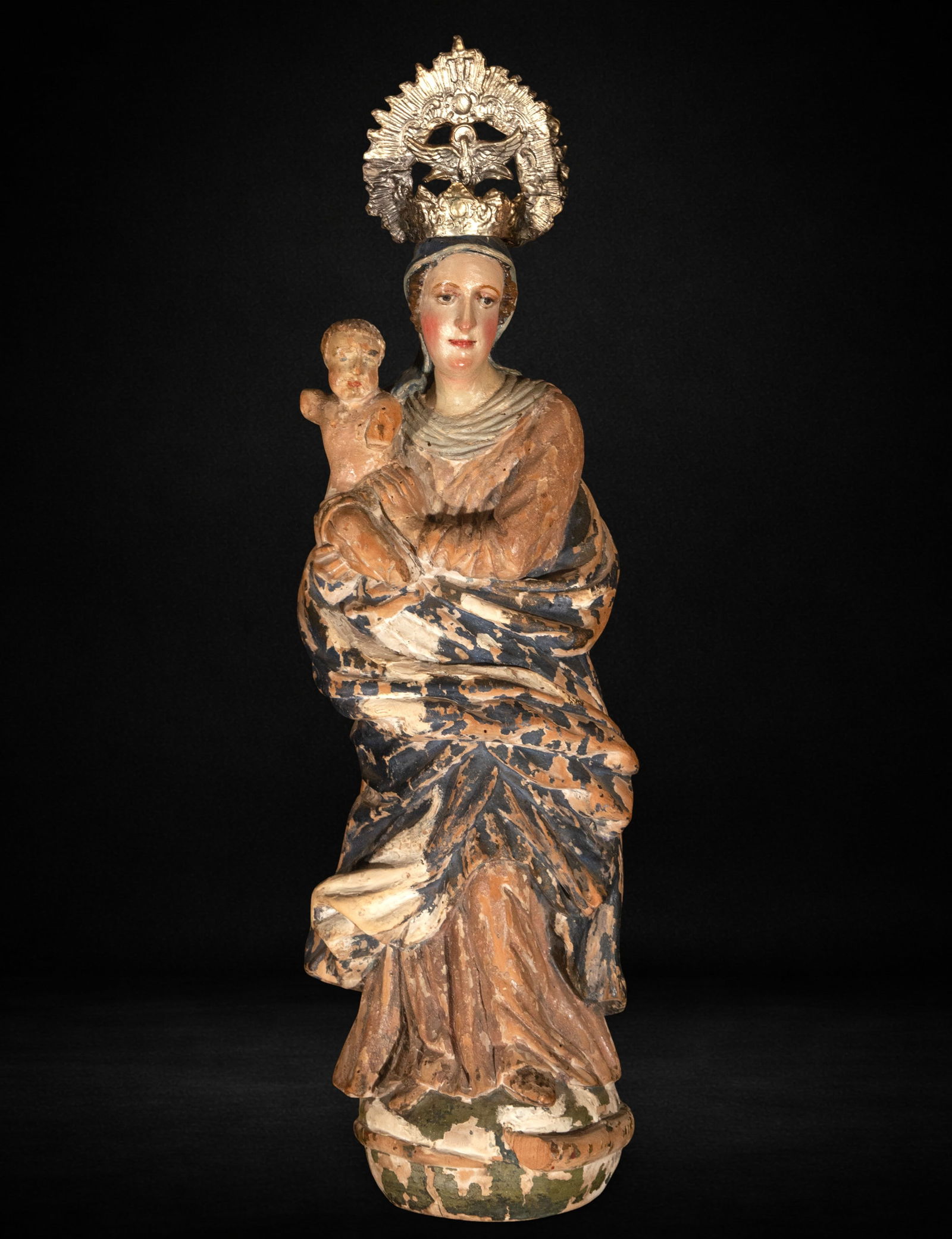 Virgin and Child. Italian School. 16th Century: Polychrome wood carving. Measures 51 x 18 x 12 cm. The Virgin is depicted seated, holding the Child in a contemplative pose, with a compact and vertical composition. The ample folds of the mantle are