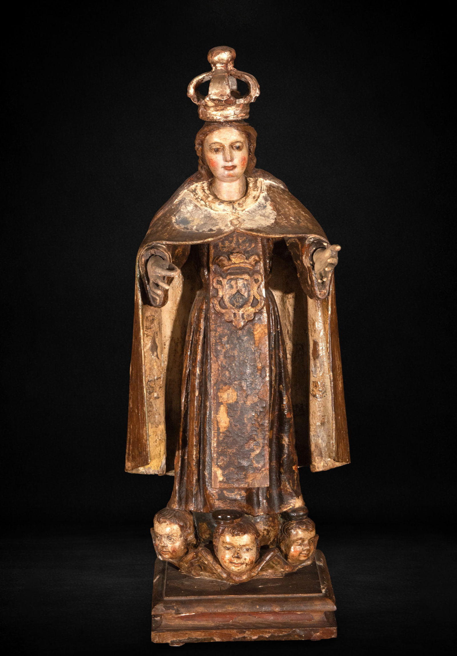 Virgin with pedestal of little angels, 17th century: Carved and polychromed wood. Measures 70 x 23 x 18 cm. Image of the Virgin Mary standing upright, crowned and with a flowing mantle, positioned frontally on a base decorated with angels' heads. The fi