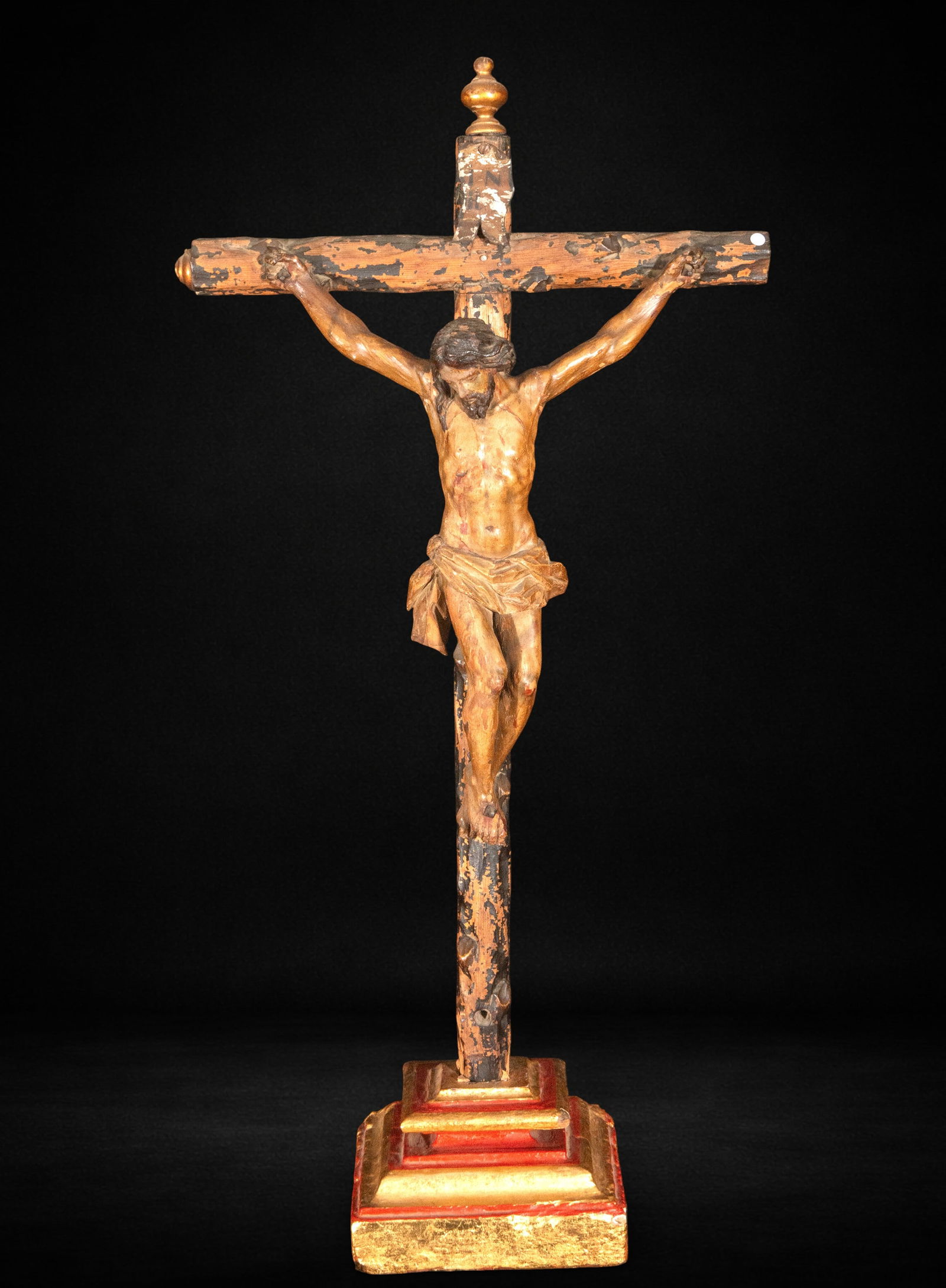Crucified Christ with restoration on the base, 17th-18th century: Carved and polychromed wood. Christ figure measures 39 x 30 x 10 cm; overall dimensions 80 x 42 x 29 cm. Image of Christ crucified with outstretched arms and head inclined towards his chest, displayin