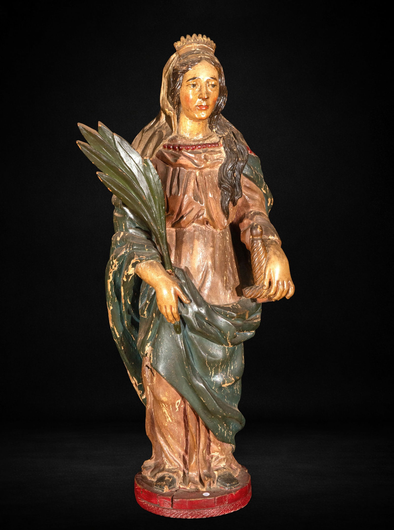 Saint Catherine of Alexandria, 18th Century: Carved and polychromed wood. Measures 70 x 27 x 19 cm. Image of Saint Catherine of Alexandria carrying the palm of martyrdom and holding a cogwheel as an iconographic attribute. She wears a tunic and