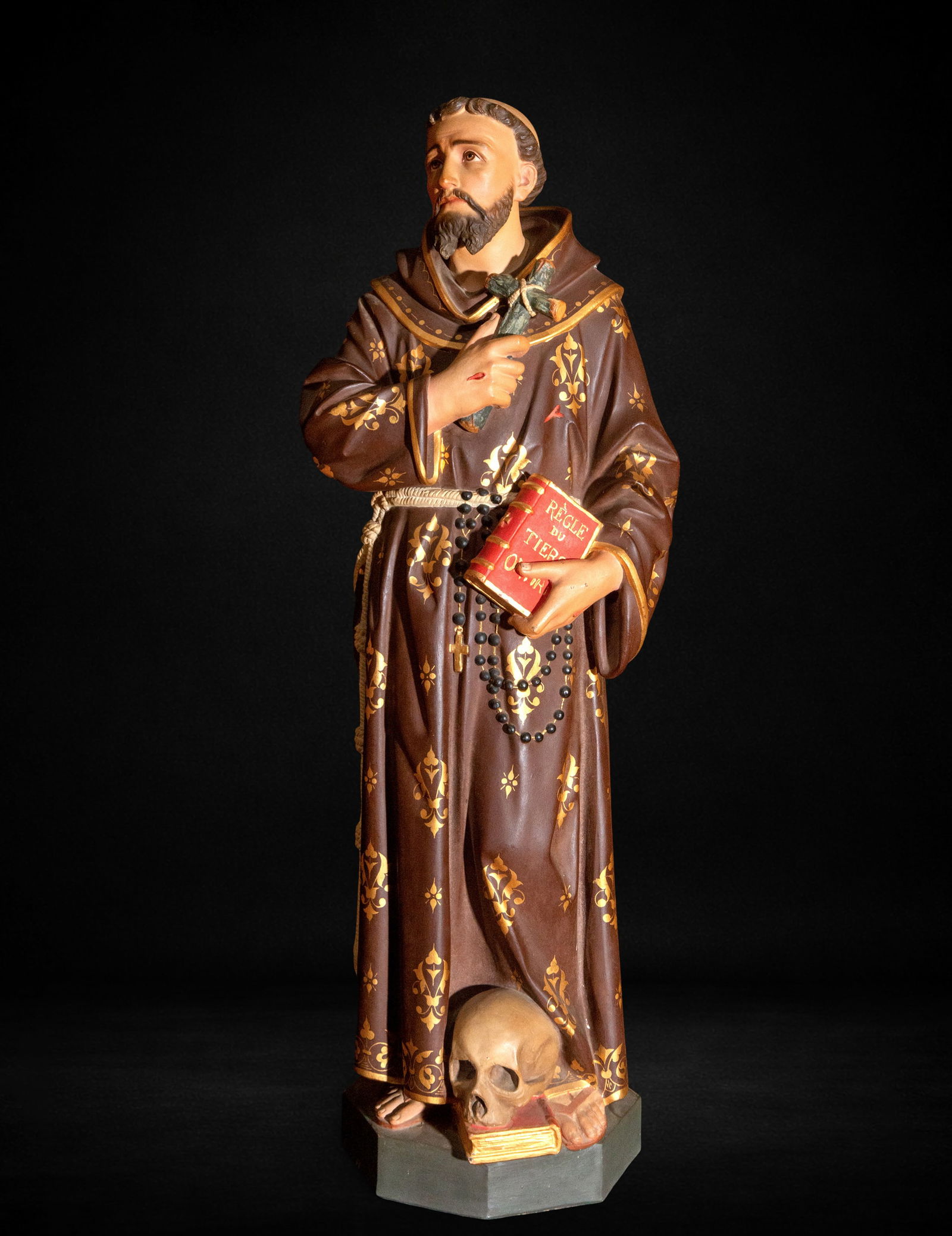 Saint Francis of Assisi, 19th Century: Polychrome terracotta. Measures 94 x 34 x 26 cm. Sculpture of Saint Francis of Assisi in a contemplative pose, slightly inclined, with his gaze raised and a withdrawn expression, holding a crucifix to