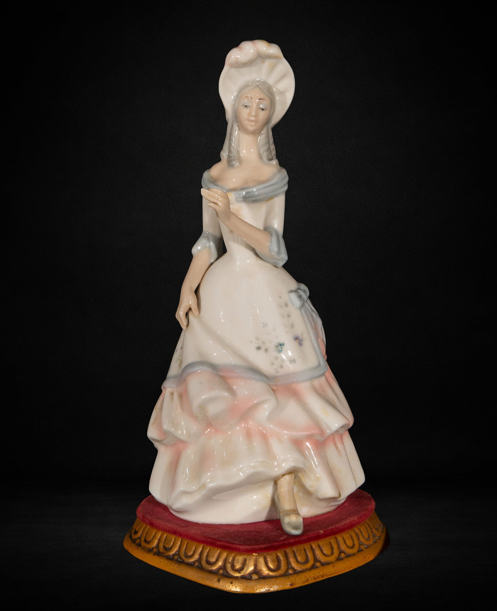 Porcelain figurine of a young lady, 20th century: Glazed and polychrome porcelain. Measures 37 x 18 x 20 cm. Female figure depicted in a flowing, ruffled dress and headdress, adopting an elegant pose with a slight bend in one leg and an arm raised in