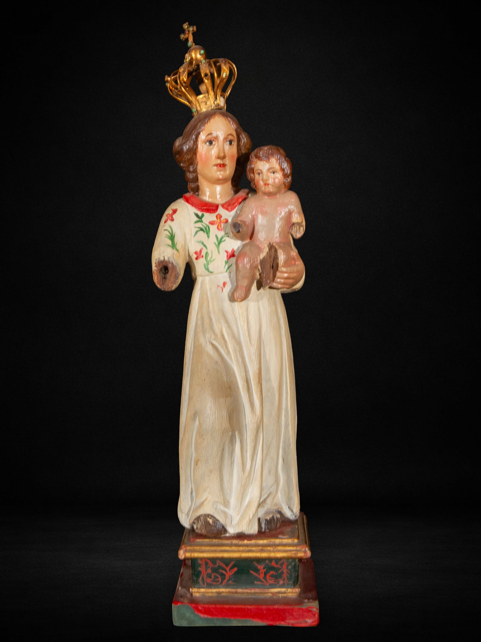 Virgin and Child, 20th Century: Carved and polychromed wood. Measures 48 x 12 x 8 cm. This sculpture in the round depicts the crowned Virgin Mary holding the Christ Child in her left arm. Both figures are depicted with well-proporti