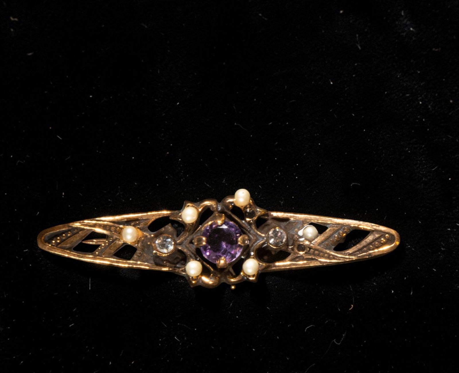 Gold-plated silver brooch with cubic zirconia and amethyst: Gold-plated silver brooch with cubic zirconia and amethyst. Its elongated shape and stylized profile feature a central motif with a round amethyst, flanked by smaller cubic zirconia and light-colored