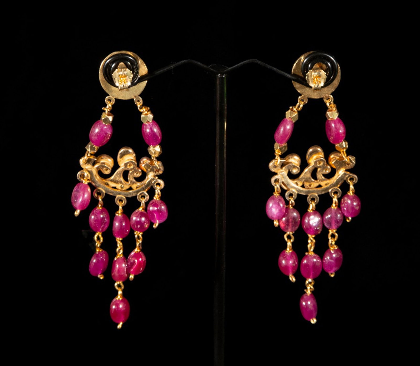 Gold-plated silver earrings with pearls and synthetic rubies: Gold-plated silver earrings with pearls and synthetic rubies. They consist of a circular upper section from which a curved, openwork structure hangs, embellished with numerous oval beads of vibrant fu