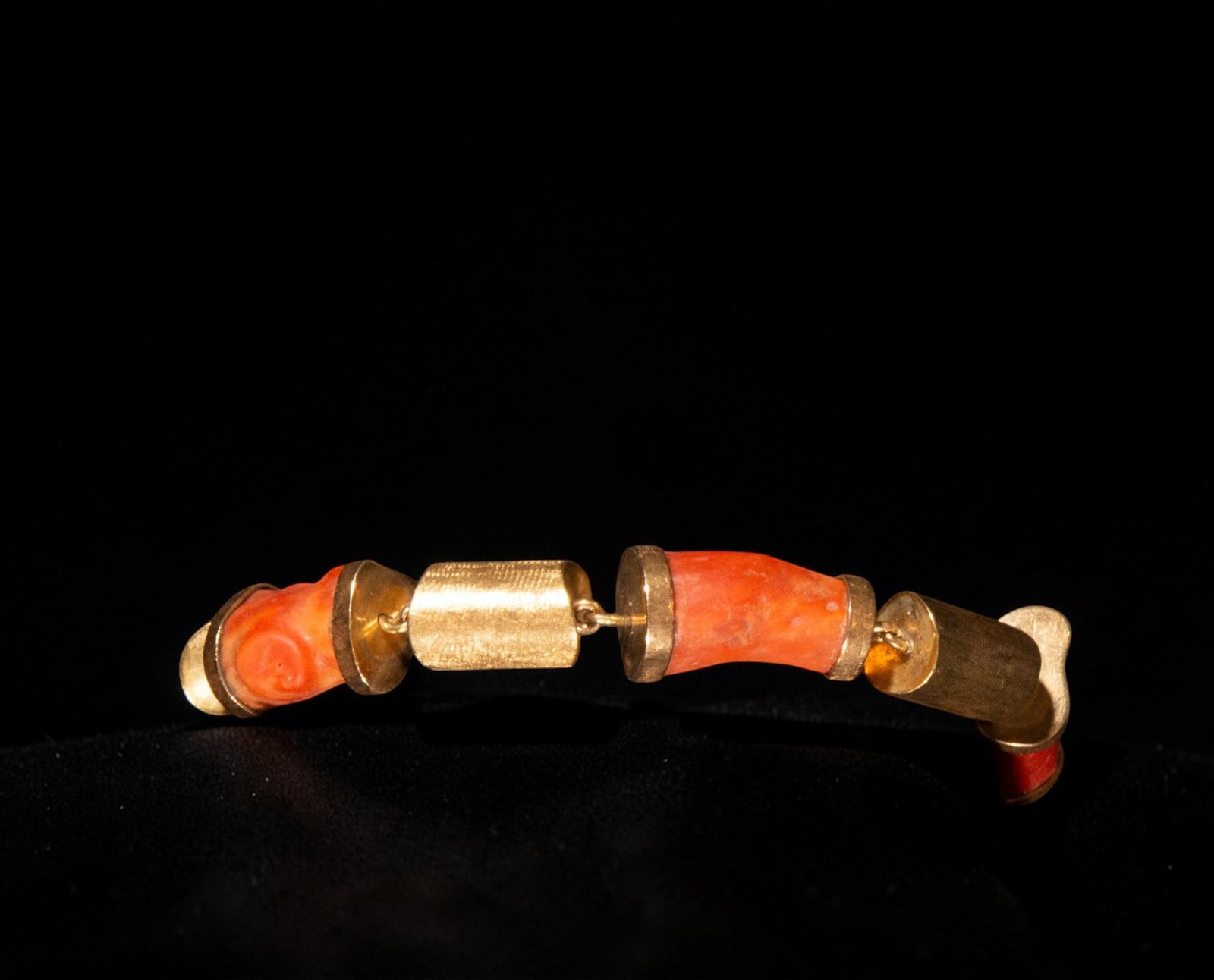 18k yellow gold bracelet with coral trunks, weight 41.04 grams: 18k yellow gold bracelet with coral trunks, weighing 41.04 grams. The piece features several irregularly shaped, orange-hued coral elements with curved, three-dimensional profiles, linked by yellow go