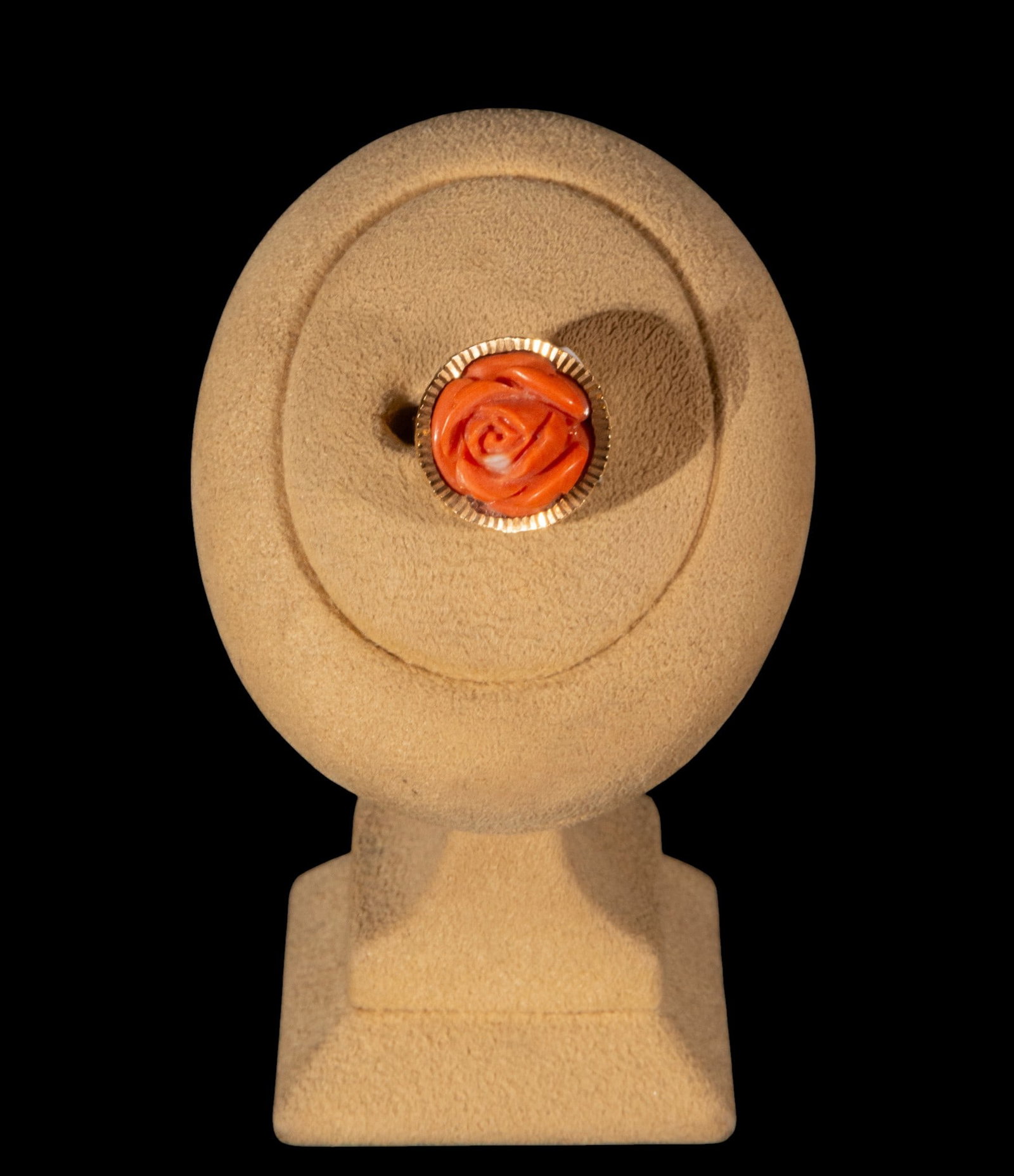 Coral pink ring: Ring with a coral rose carved in relief, mounted on a metal band. The piece is based on a rounded floral carving with overlapping petals and a spiral center, rendered in a pinkish-orange hue. The main