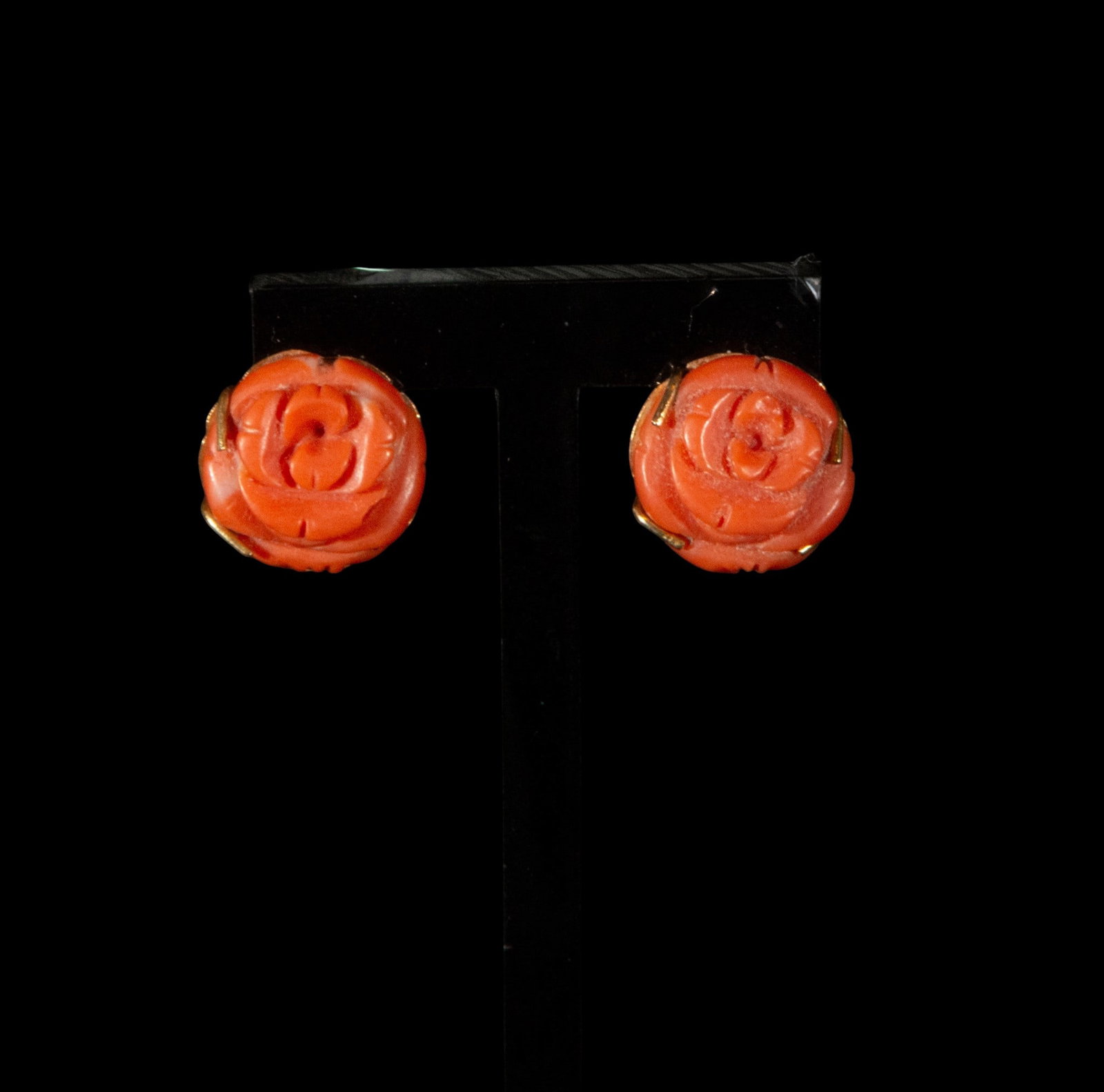 Coral and gold flower earrings: Coral and gold earrings with a floral motif, each composed of a coral rose carved in relief and held in place by a gold setting. The focus of each earring is on the intricate carving of the coral, fea