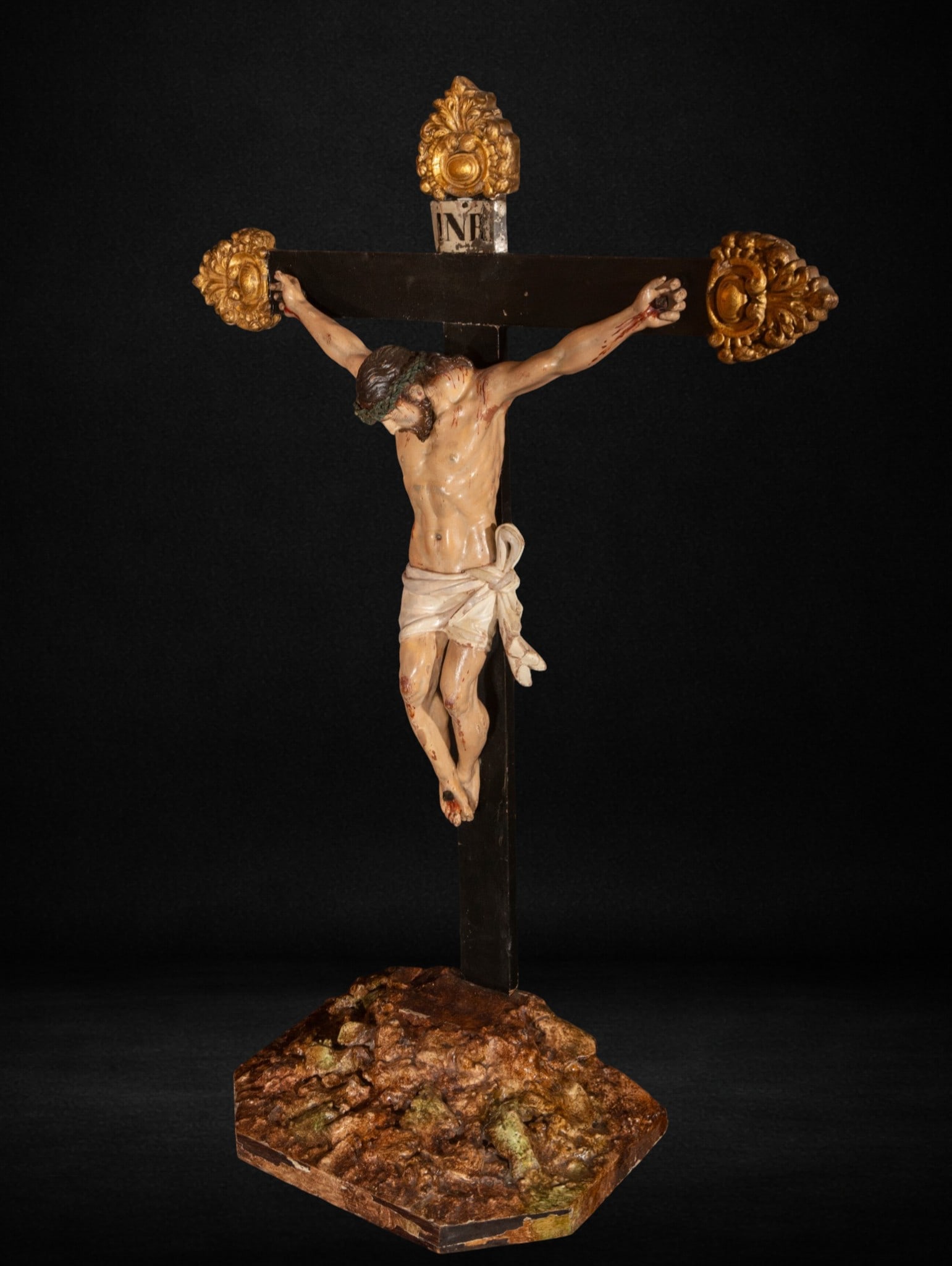Important Christ on the Cross, Sevillian Master of the 17th century: Carved and polychromed wood. Image measures 44 x 42 cm; cross 95 x 10 cm; overall 64 x 26 cm.