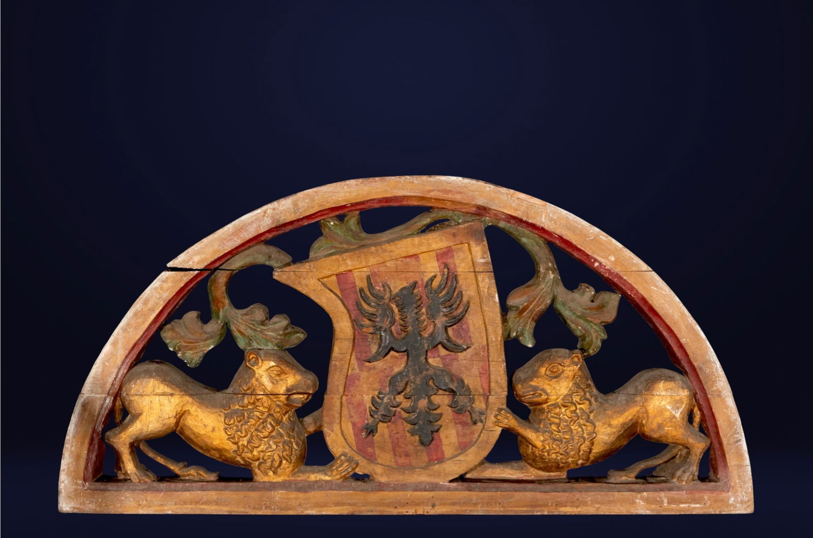 Crescent finial with heraldic shield, possibly Austro-Hungarian, 17th century: Carved and polychromed wood. Dimensions: 63 × 126 × 11 cm. Semicircular architectural finial with a central shield flanked by facing animals and openwork vegetal scrolls. The piece combines decorati