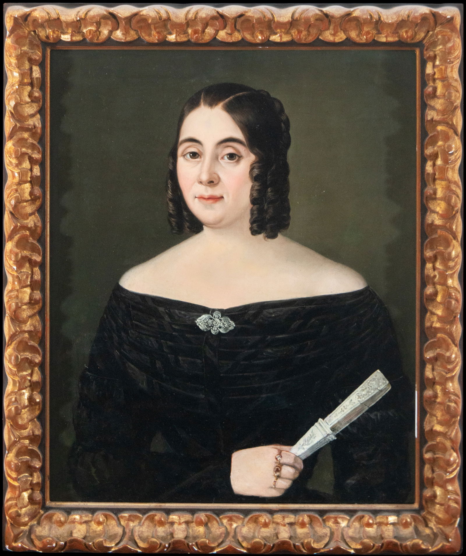 Portrait from the 1900s European School, 19th Century: Oil on panel. Dimensions: 68 x 53 cm; 83 x 63 cm with frame. Half-length portrait of a woman against a neutral background, wearing a black dress, holding a closed fan, and wearing understated jewelry.