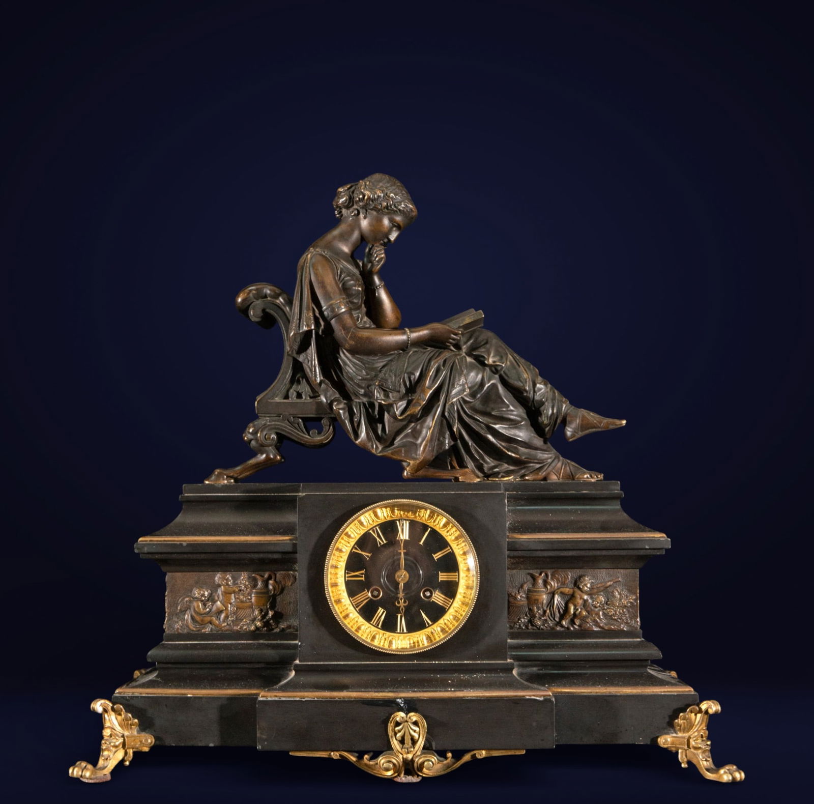 Table clock with a female figure reading, French neoclassical style, 20th century: Patinated bronze and black marble. Measures 50 x 52 x 25 cm. Mantel clock crowned by a reclining female figure in a meditative pose, holding a book, atop a stepped architectural structure with austere