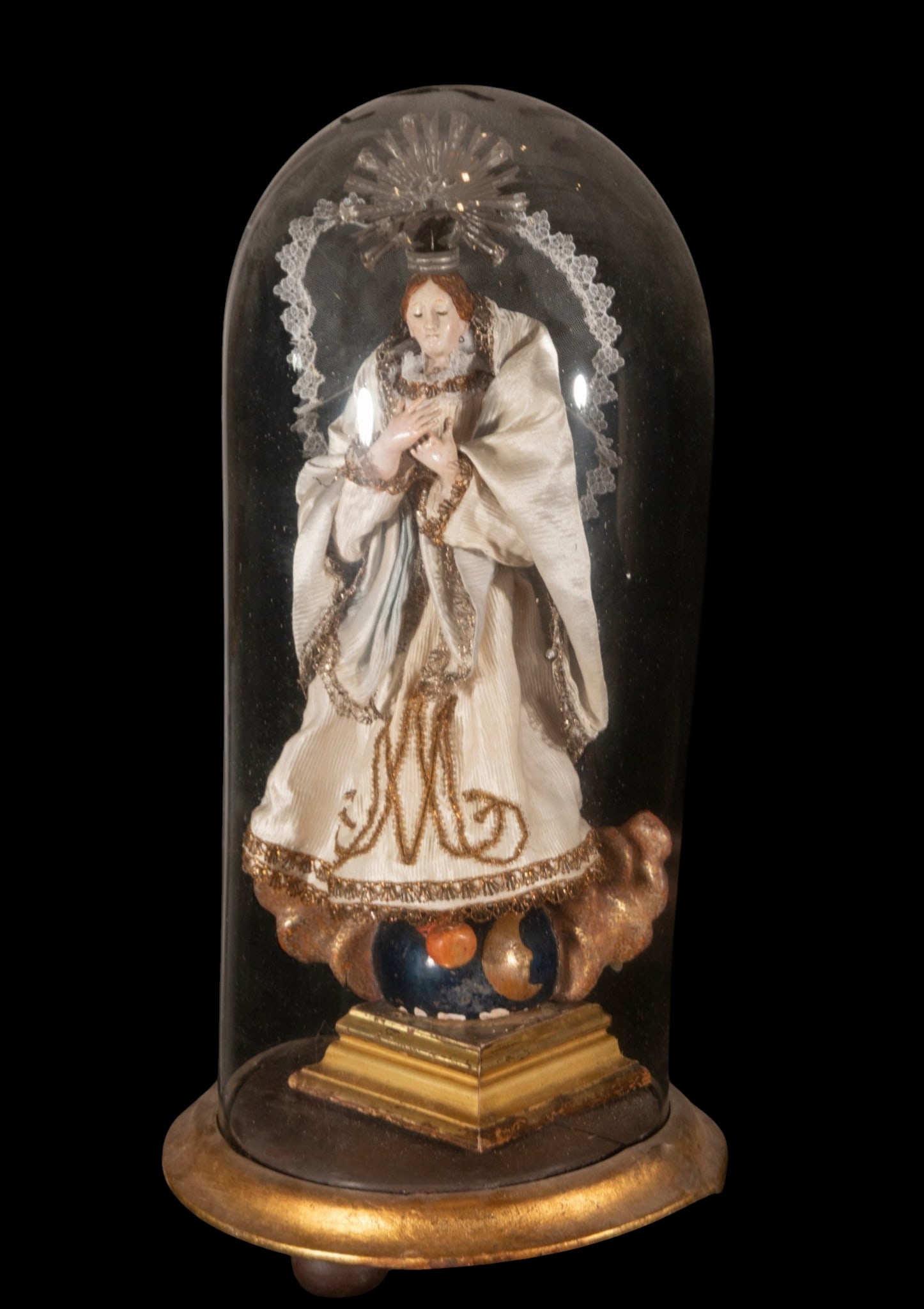 Virgin in a Neapolitan lantern - 19th or 20th century: Dressed figure under a glass dome, with textile elements and a gilded wooden base, probably. Measures 46 x 18 x 12 / 57 x 28 x 28 cm.