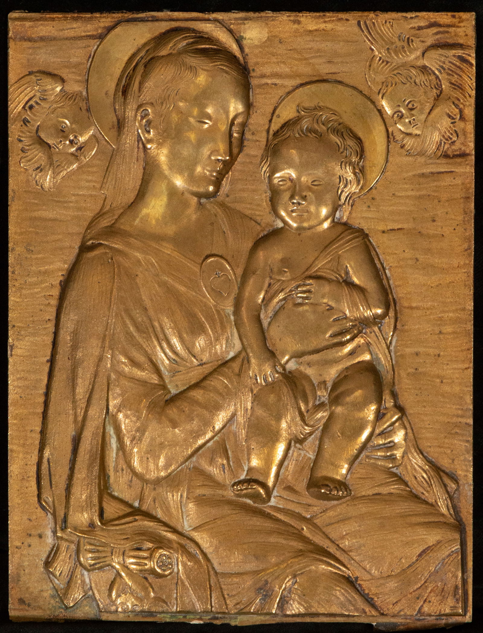 Bronze plaque with Virgin and Child, European school, 17th-18th century: Bronze relief. Measures 19 x 15 cm. Devotional plaque depicting the Virgin Mary seated and holding the Christ Child, flanked by small angel heads in the upper corners. The figure is rendered in a soft