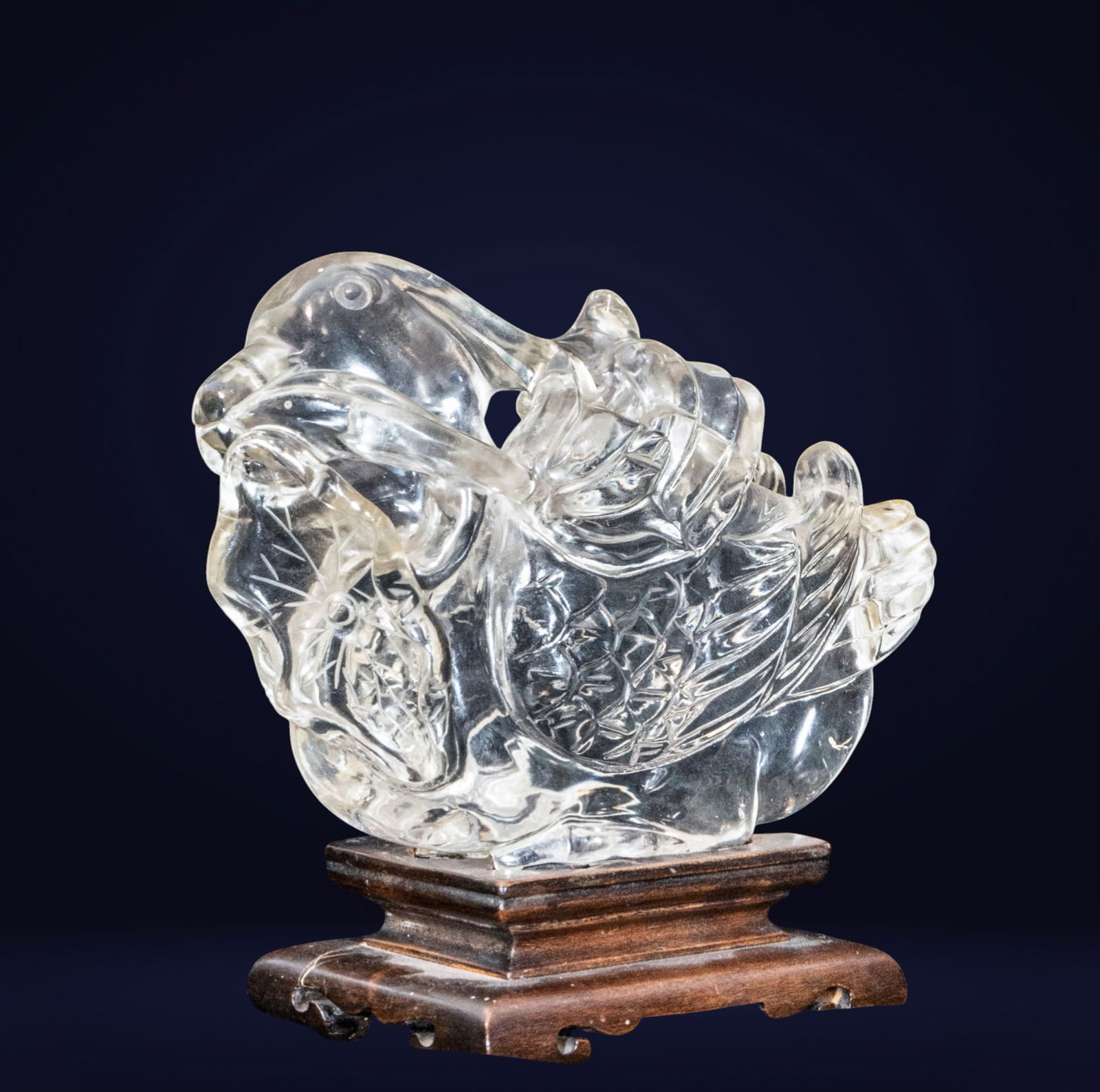 Oriental bird, Chinese school, 19th century: Cut and polished rock crystal on a wooden base. Measures 15 x 16 x 7 cm. Zoomorphic figure rendered with rounded and compact forms, in which the bird appears curled up with a synthetic treatment of th
