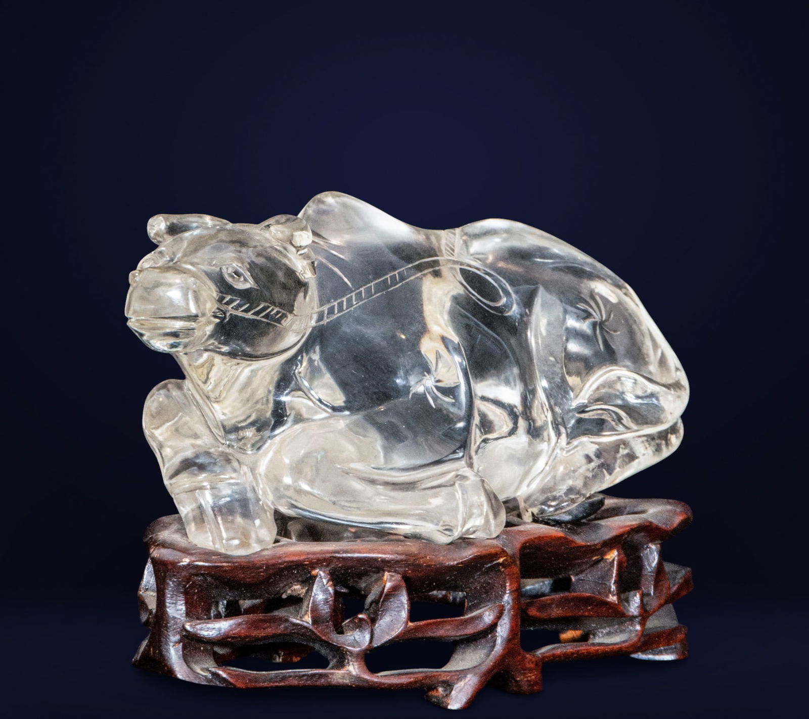 Reclining ox, Chinese School, 19th century: Carved and polished rock crystal on a wooden base. Measures 10 x 14 x 7 cm. Sculpture of an ox in a recumbent pose, with its body positioned horizontally and its head slightly raised, features that co