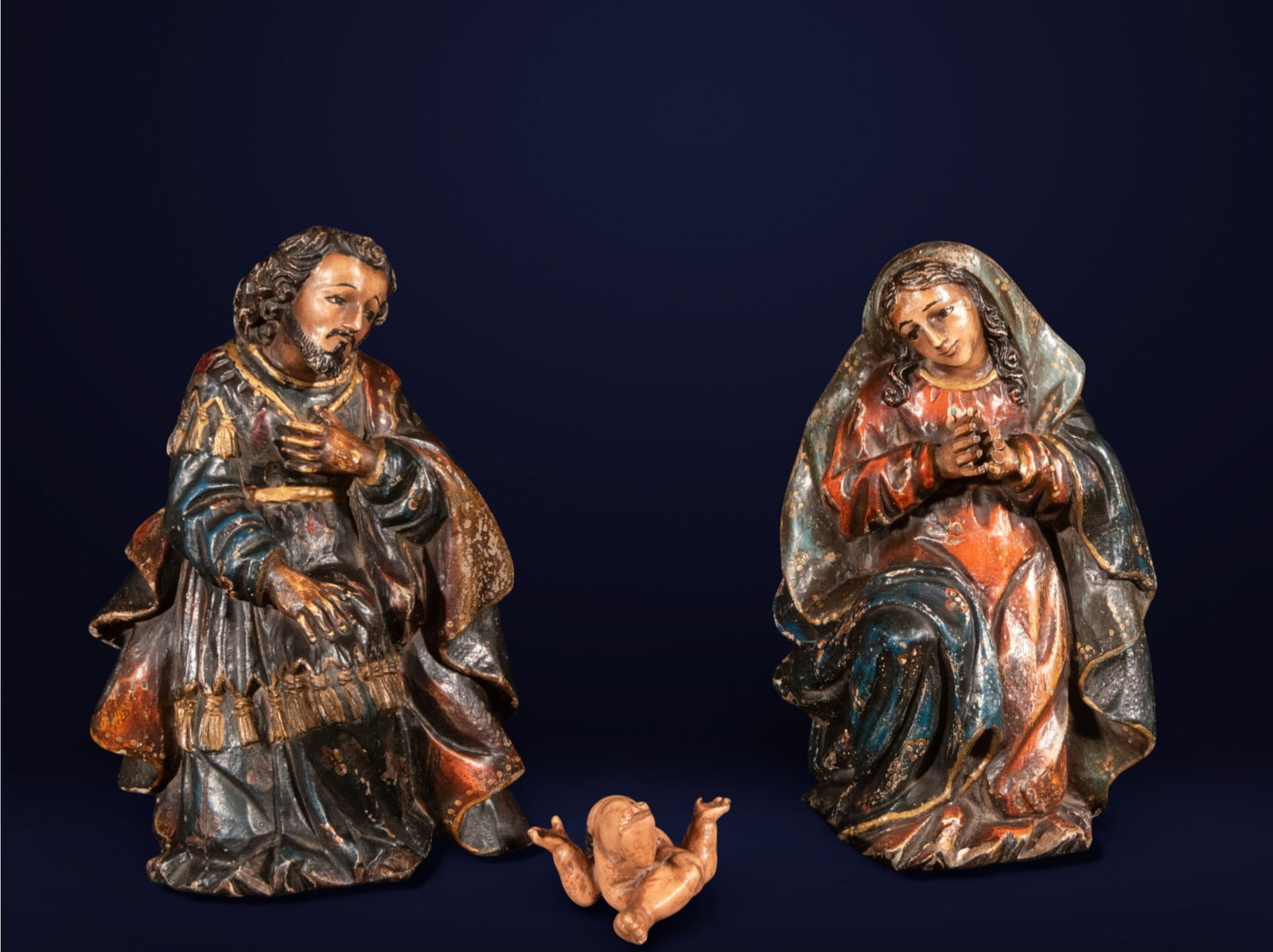 Nativity scene in polychrome wood carving, colonial school, 19th century: Carved and polychromed wood. Measurements: Saint Joseph 23 x 16 x 14 cm, Virgin Mary 23 x 16 x 14 cm (approx.), and Child Jesus 10 x 7 x 5 cm. Nativity group composed of Saint Joseph and the Virgin Ma