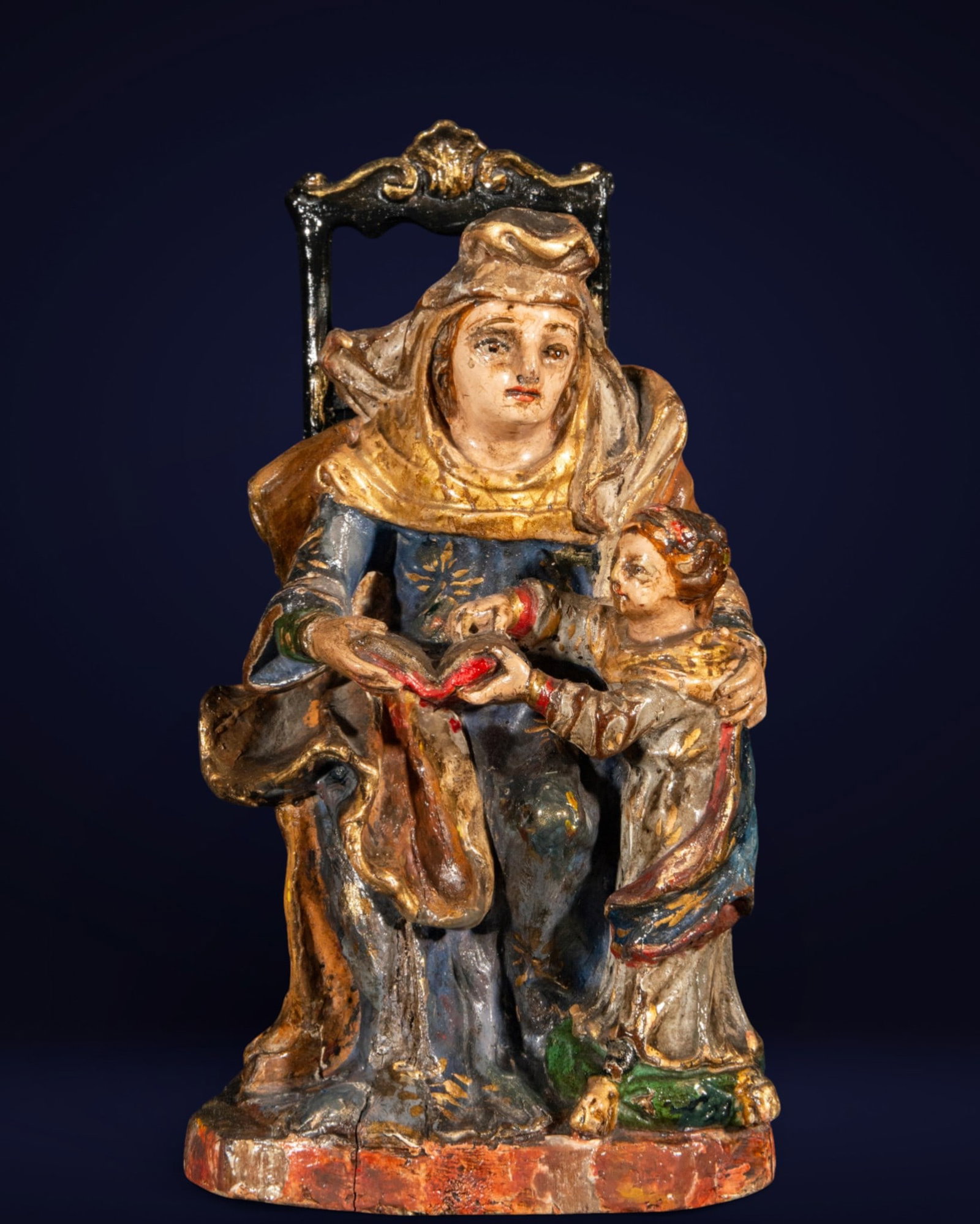 Saint Anne teaching the Virgin Mary to read, Spanish school, 17th century: Carved and polychromed wood. Measures 18 x 12 x 8 cm. Sculptural group depicting Saint Anne seated with the Virgin Mary as a child at her side, united by the open book that centers the action and unde