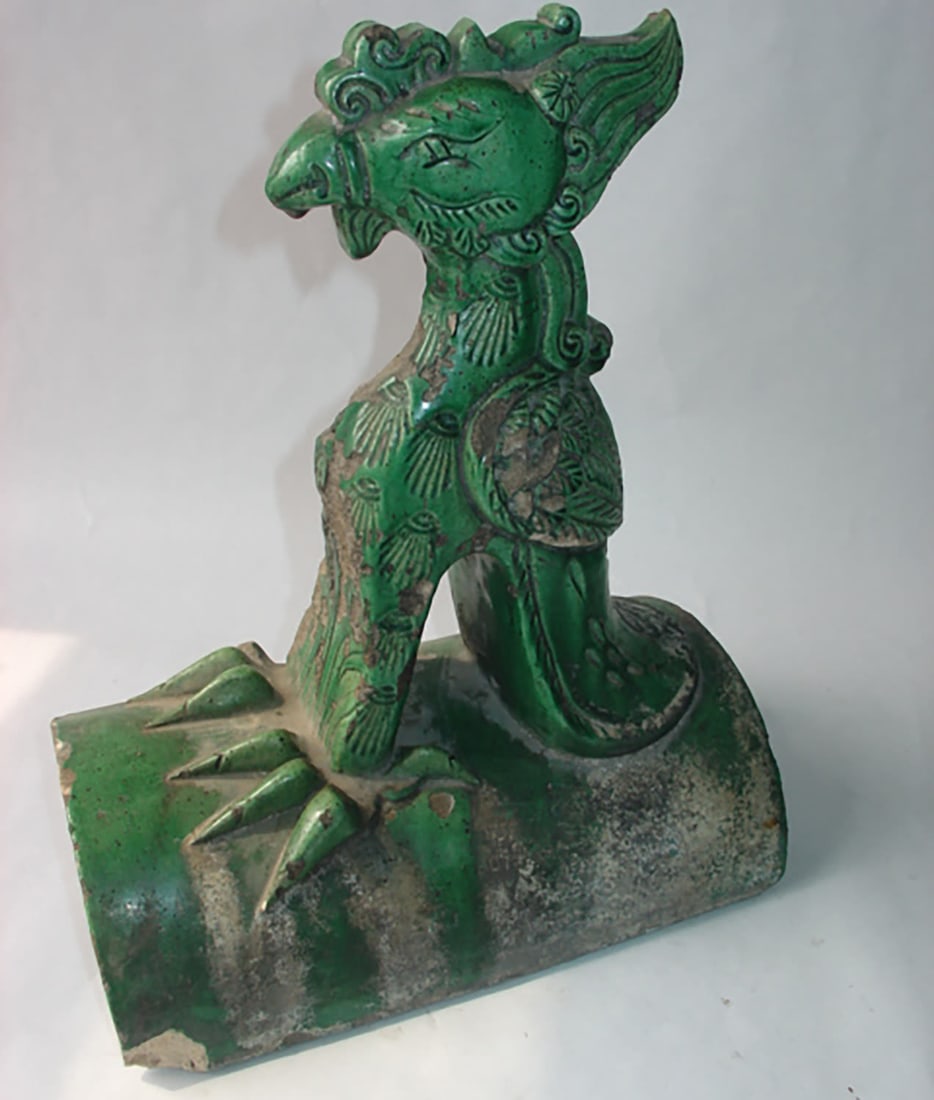 Ridge tile topped with a stylized phoenix. Terracotta with a monochromatic green glaze. Porcelain.: Ridge tile topped with a stylized phoenix. Terracotta with a green monochrome glaze. Porcelain. Ming Dynasty. 1368 to 1644. Height 34cm x Length 31 x Width 16cm. Significant lack of glaze and chips. C