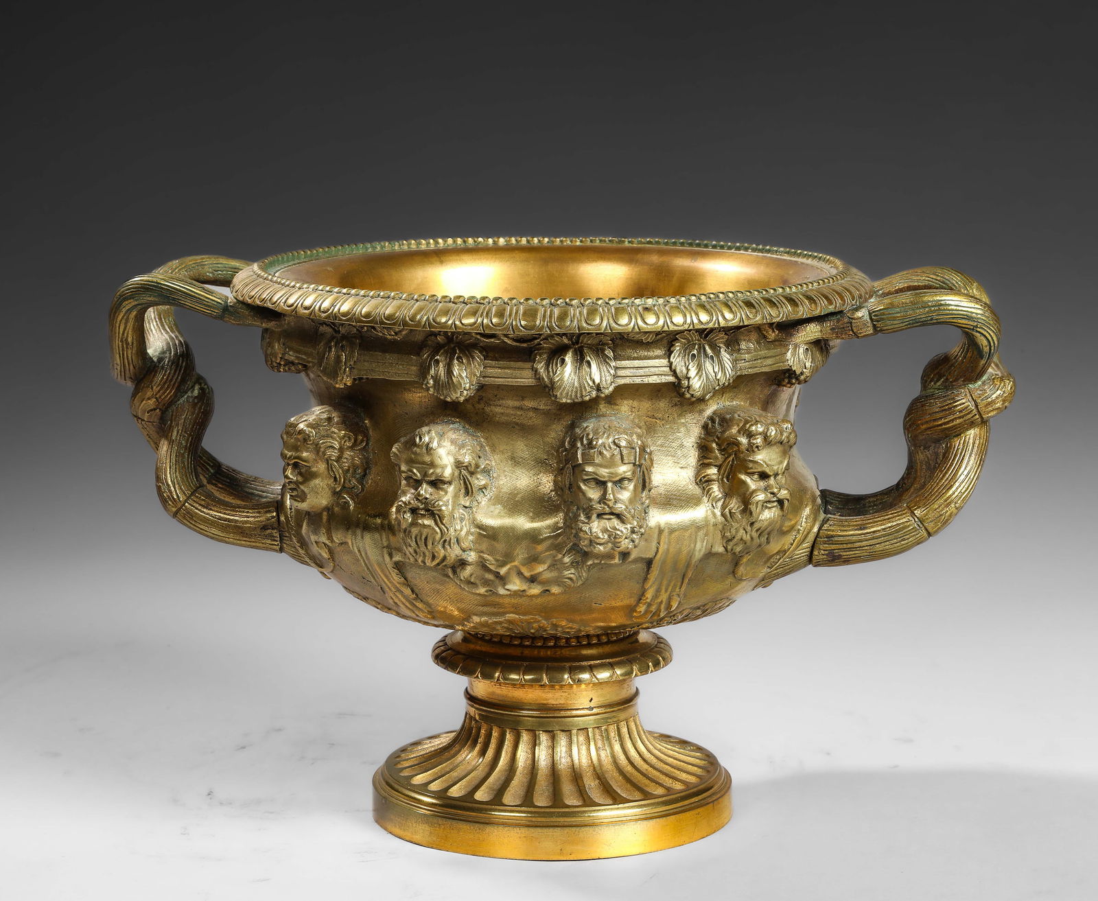 Medici Grand Tour Cup with Greek Satyrs in the Classical Greek Style, in Bronze. 18th Century: Bowl on pedestal forming a basin with scrolled handles, molded with heads of mythological deities. Bronze. Height 20 cm x diameter 35 cm. Lot in international warehouse (outside the EU). For shipments