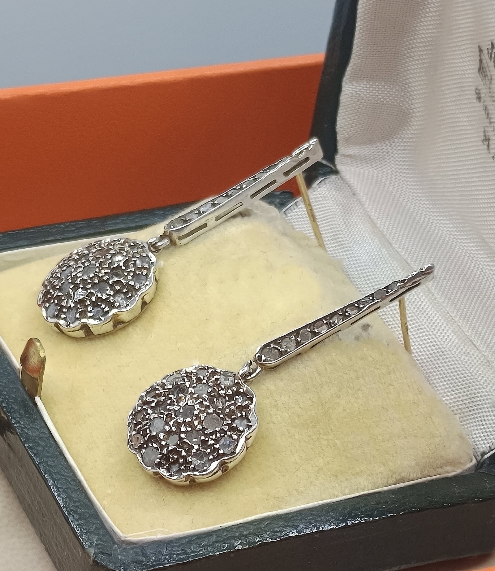 CASE WITH ANTIQUE 14K GOLD PENDANT EARRINGS AND 60 DIAMONDS: WEIGHT: 7.0 GRAMS. DANGLE EARRINGS WITH 14K GOLD ROSETTES AND A TOTAL OF 60 ANTIQUE ROSE-CUT DIAMONDS. WITH LEATHER BOX. HALLMARKS ON BOTH POSTES: 585. LATER PERIOD SILVER CLASPS FOR A MORE ADJUSTABLE