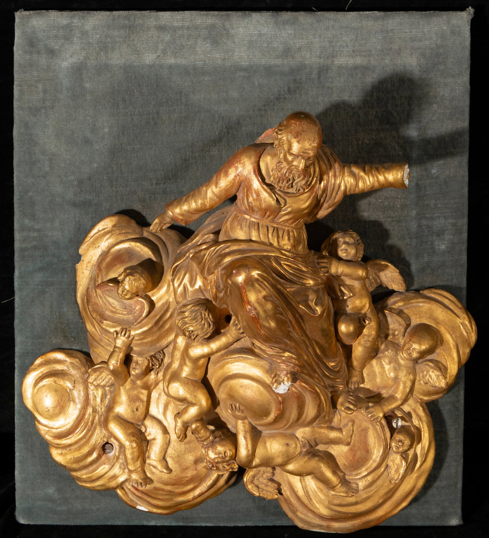 Eternal Father. Spanish School. 19th Century: Gilded terracotta. Dimensions: 38 x 40 cm. Sculptural relief depicting the Eternal Father surrounded by cherubs among clouds, crafted with great Baroque dynamism. The gilded surface intensifies the ef