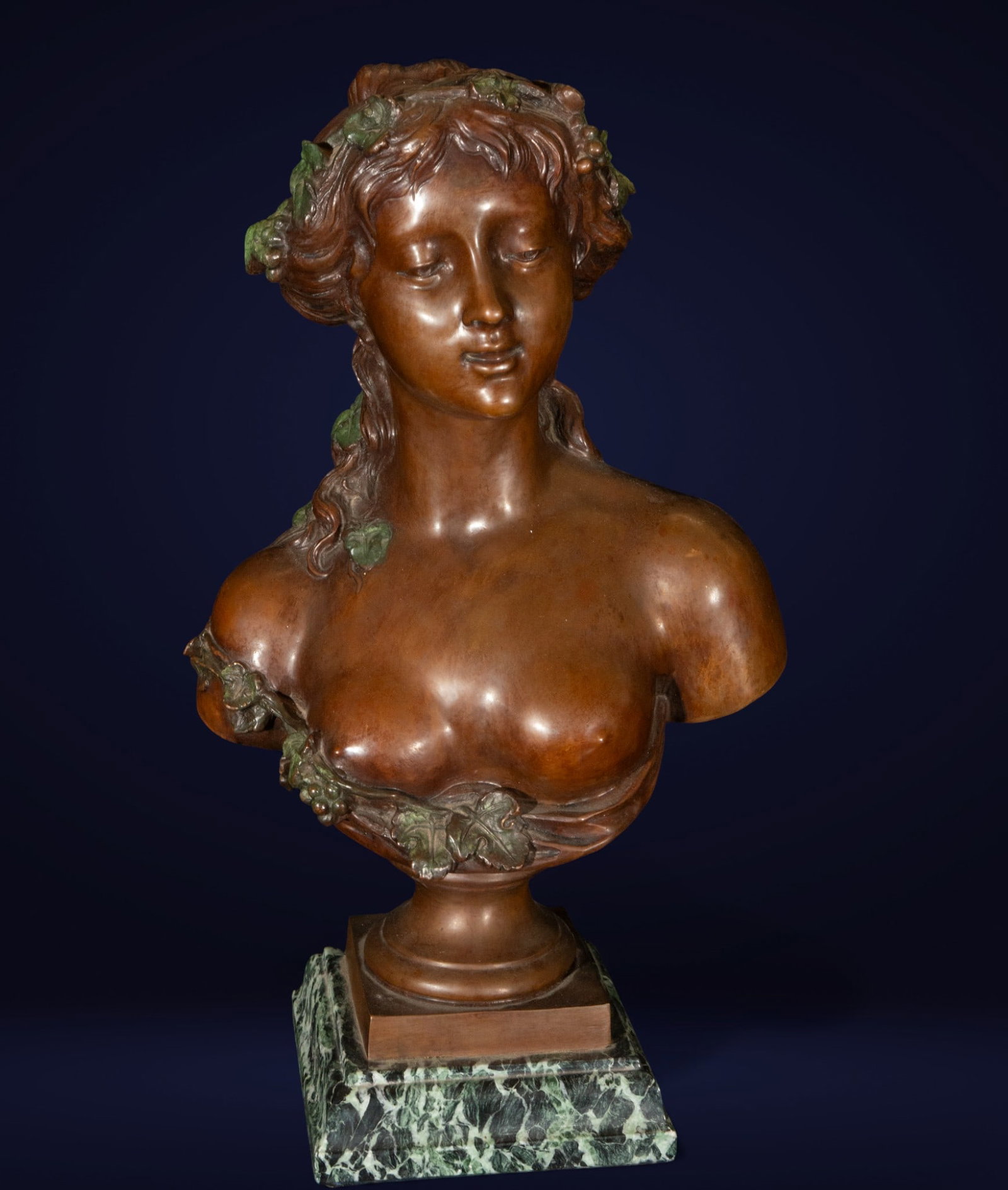 Female bust with garlands. French School. 19th century.: Patinated bronze with a green marble base. Measures 65 x 38 x 26 cm. Bust of a young woman with a crown of leaves and bunches of grapevines, a symbol of nature and abundance. The soft modeling of the