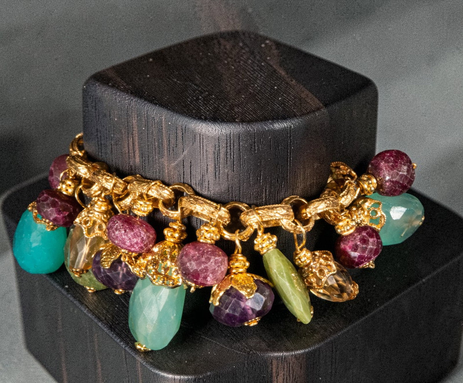 Gold-plated silver bracelet with amethysts, chalcedony, and citrine quartz: Gold-plated silver bracelet with amethysts, chalcedony, and citrine quartz. It features ornamental links from which hang beads and pendants carved from various stones, including violet amethysts, blue
