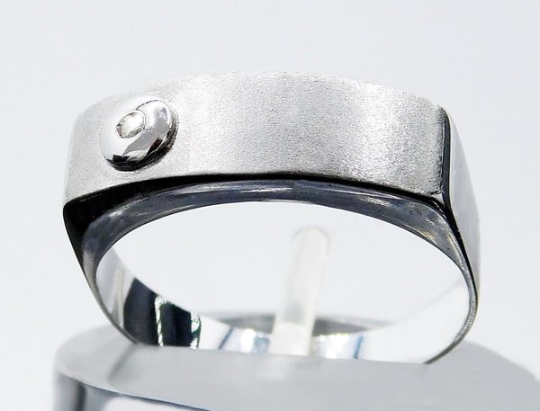 750 white gold ring with diamond, Weight: 3.5 grams.: 18k white gold (750) with diamond. Original design ring with a polished white gold band and a matte front, decorated with a small diamond in a bezel setting. Hallmarked 750. Brilliant-cut diamond: 0.0