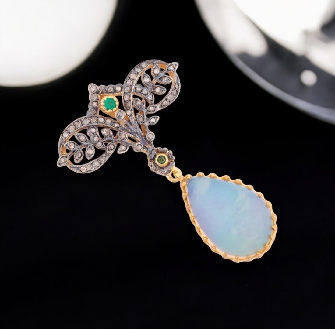 Pendant with opal, emeralds and diamonds: A 925 sterling silver pendant with gilt plating, finished with a 14-karat gold bail, featuring a teardrop-shaped opal as its centerpiece, weighing approximately 3 carats. The opal is flanked by a flor