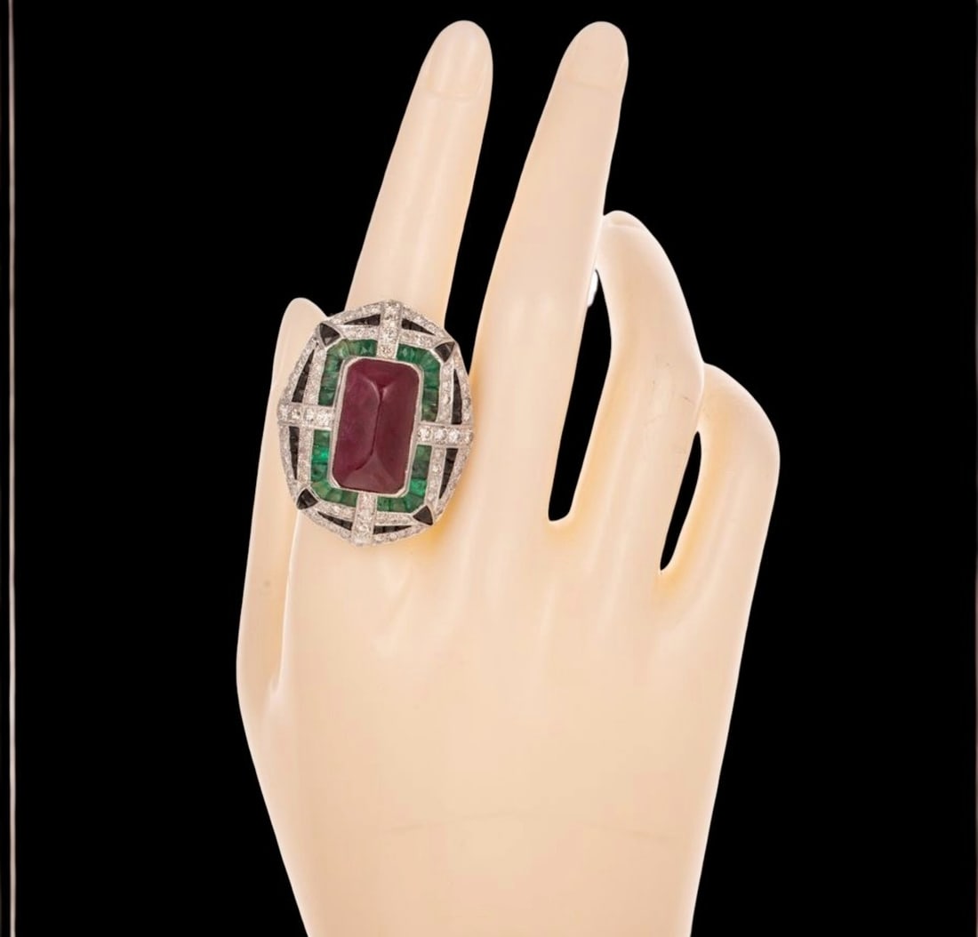 Ring with central ruby, emeralds, onyx and diamonds: A geometric band ring crafted in silver with a gilt finish, featuring a rectangular-cut natural ruby ??weighing approximately 10 carats, framed by a composition of onyx and emeralds, all enhanced by b