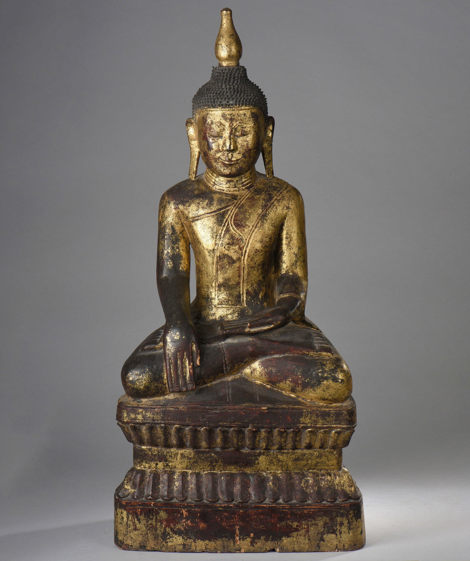 Seated Marawijaya Buddha - Burma. Ava Kingdom. 18th century. 76 cm.: Buddha Marawijaya seated on a tall lotus-shaped base, with one hand in bumishparshamudra and the other in dhyanamudra, wearing the ushnisha and a tall rasmi. Lacquered and gilded wood. Burma. Kingdom 