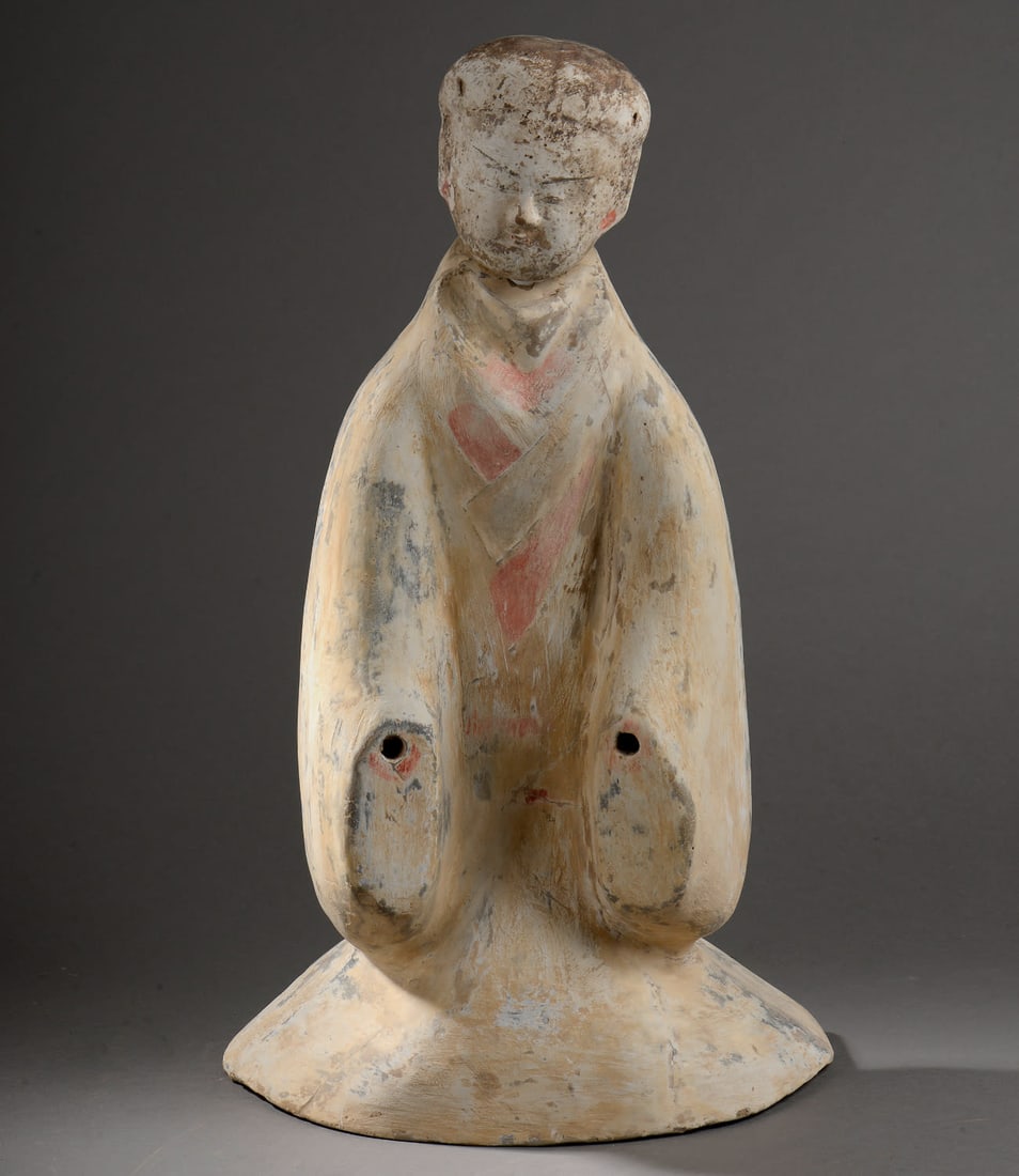Dignitary: Stylized, removable head, shown kneeling, wearing a long, draped tunic with wide sleeves.: DignitaryStylized, removable head, shown kneeling, wearing a long, draped tunic with wide sleeves. Grey terracotta with traces of slip and polychrome pigments. Porcelain. Han Dynasty. 206 before to 22