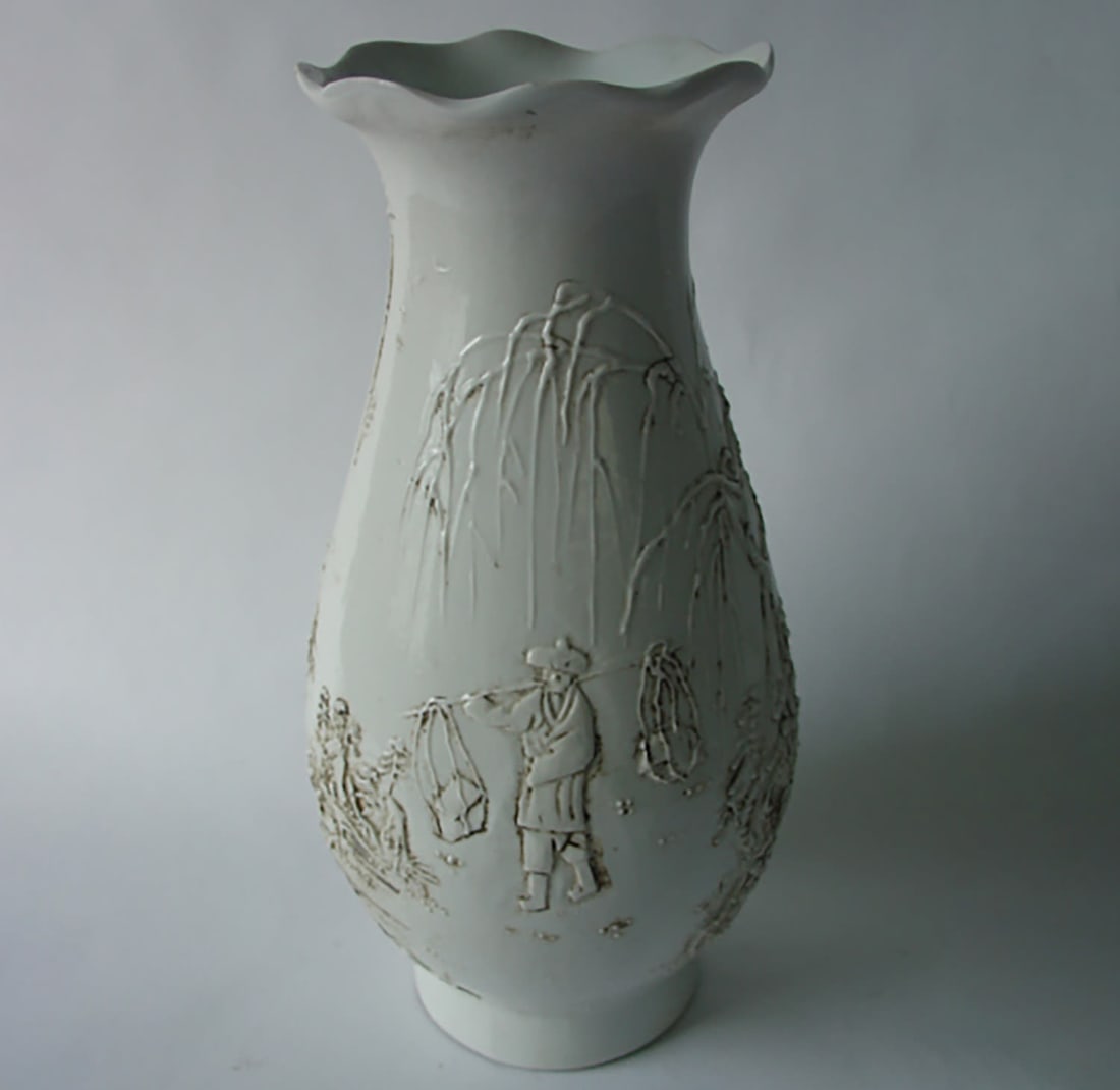 An ovoid vase with a multi-lobed opening in white Chinese porcelain, molded with a decoration of a: ovoid vase with a multi-lobed opening in white Chinese porcelain, molded with decoration of a figure under a weeping willow. China and Qing dynasty, 20th century. Height 24 cm. Diameter at the neck 9 