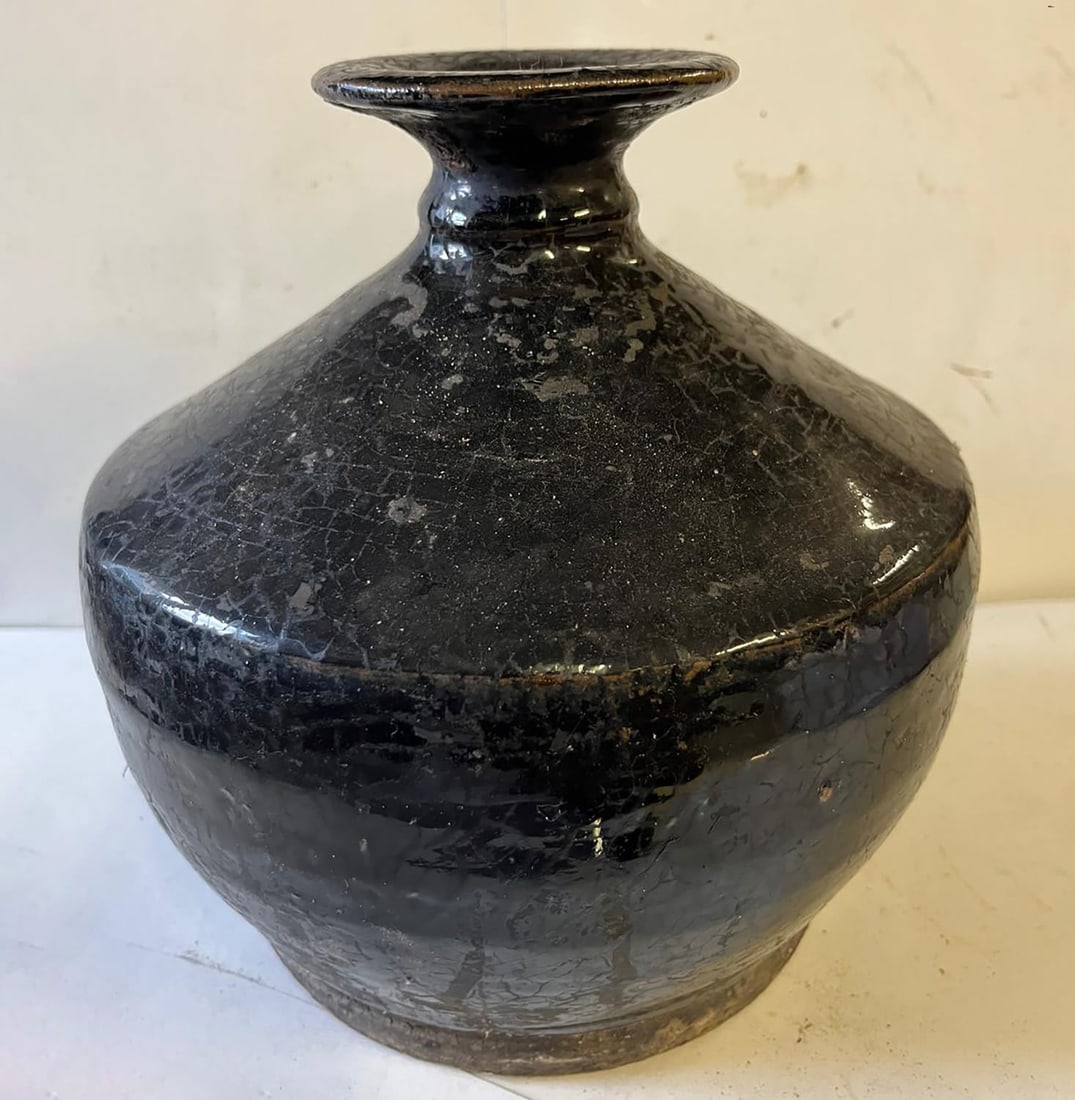 Wide-bodied bottle with a sloping shoulder and a small flared neck in thick stoneware with a: Bottle with a wide body, sloping shoulder and a small flared neck in thick stoneware with a monochrome black glaze. Porcelain. Ming Dynasty. 1368 to 1644. Height 23 cm x diameter 9.5 cm. Porcelain. Ch